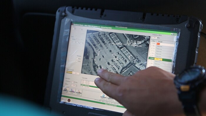 Staff Sgt. Jordan Kelly, a fire power control team chief with 1st Air Naval Gunfire Liaison Company, points out a target on a video scout during close air support training in Lake Havasu City, Arizona, April 13, 2015. The video from the F/A-18 Hornet’s sensors allows the Marines to confirm enemy target locations with the pilot.
