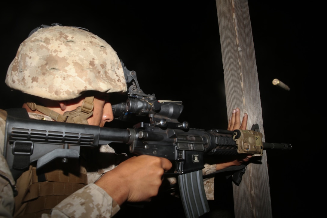 Pfc. Alexander Pindea, a Marine with 3rd Radio Battalion, fires an M4 5.56mm carbine rifle during the unknown distance night shoot as part of the marksmanship coach's course at the Kaneohe Bay Range Training Facility, April 13, 2015. The Marines are the first cycle of coaches in training to fire on the modified tables of fire, tables two through six, which have replaced tables three through four. (U.S. Marine Corps photo by Lance Cpl. Adam O. Korolev/Released)