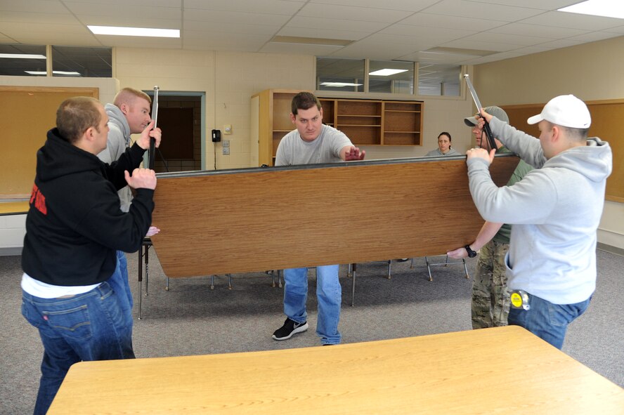 Airmen from Grand Forks Air Force Base arrange furniture in a Carl Ben Eielson Elementary School classroom April 8, 2015, on Grand Forks Air Force Base, N.D. The incoming Air Mobility Command Inspector General capstone team will utilize a series of classrooms at the school for group interviews with members of the base. (U.S. Air Force photo by Staff Sgt. David Dobrydney/Released)