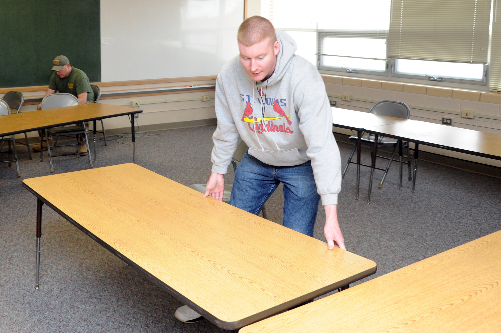 Senior Airman James Donoho, 319th Security Forces Squadron, arranges tables in a Carl Ben Eielson Elementary School classroom April 8, 2015, on Grand Forks Air Force Base, N.D. The incoming Air Mobility Command Inspector General capstone team will utilize a series of classrooms at the school for group interviews with members of the base. (U.S. Air Force photo by Staff Sgt. David Dobrydney/Released)