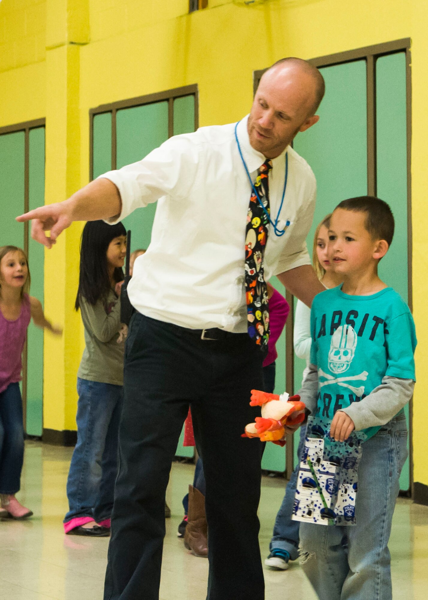Stephensen Elementary School principal Phil McCluskey helps direct children back to their seats after receiving their own personal “Ruffy” toys at Mountain Home Air Force Base, April 2, 2015. The Mountain Home School District has discovered students in second grade receive the most educational benefit from reading initiatives. (U.S. Air Force photo by 2nd Lt. Kip Sumner/RELEASED)