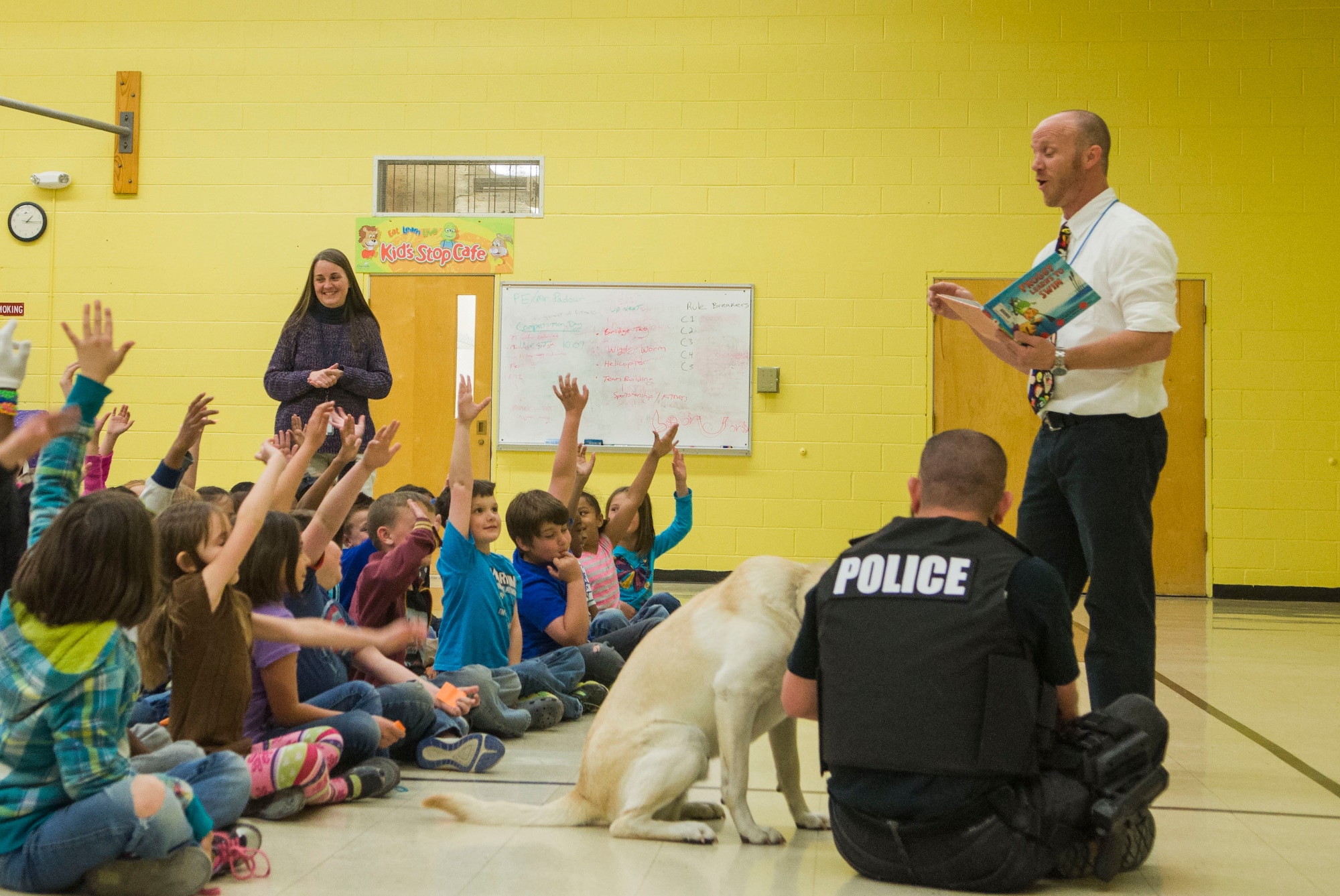Second grade students from Stephensen Elementary School raise their hands to answer Principal Phil McCluskey’s question at Mountain Home Air Force Base, April 2, 2015. McCluskey purposefully stopped reading a story at a cliffhanger, and asked the children “what happens next?” in an effort to spark their curiosity to finish the story on their own. (U.S. Air Force photo by 2nd Lt. Kip Sumner/RELEASED)