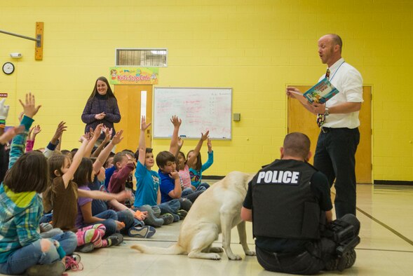 Second grade students from Stephensen Elementary School raise their hands to answer Principal Phil McCluskey’s question at Mountain Home Air Force Base, April 2, 2015. McCluskey purposefully stopped reading a story at a cliffhanger, and asked the children “what happens next?” in an effort to spark their curiosity to finish the story on their own. (U.S. Air Force photo by 2nd Lt. Kip Sumner/RELEASED)
