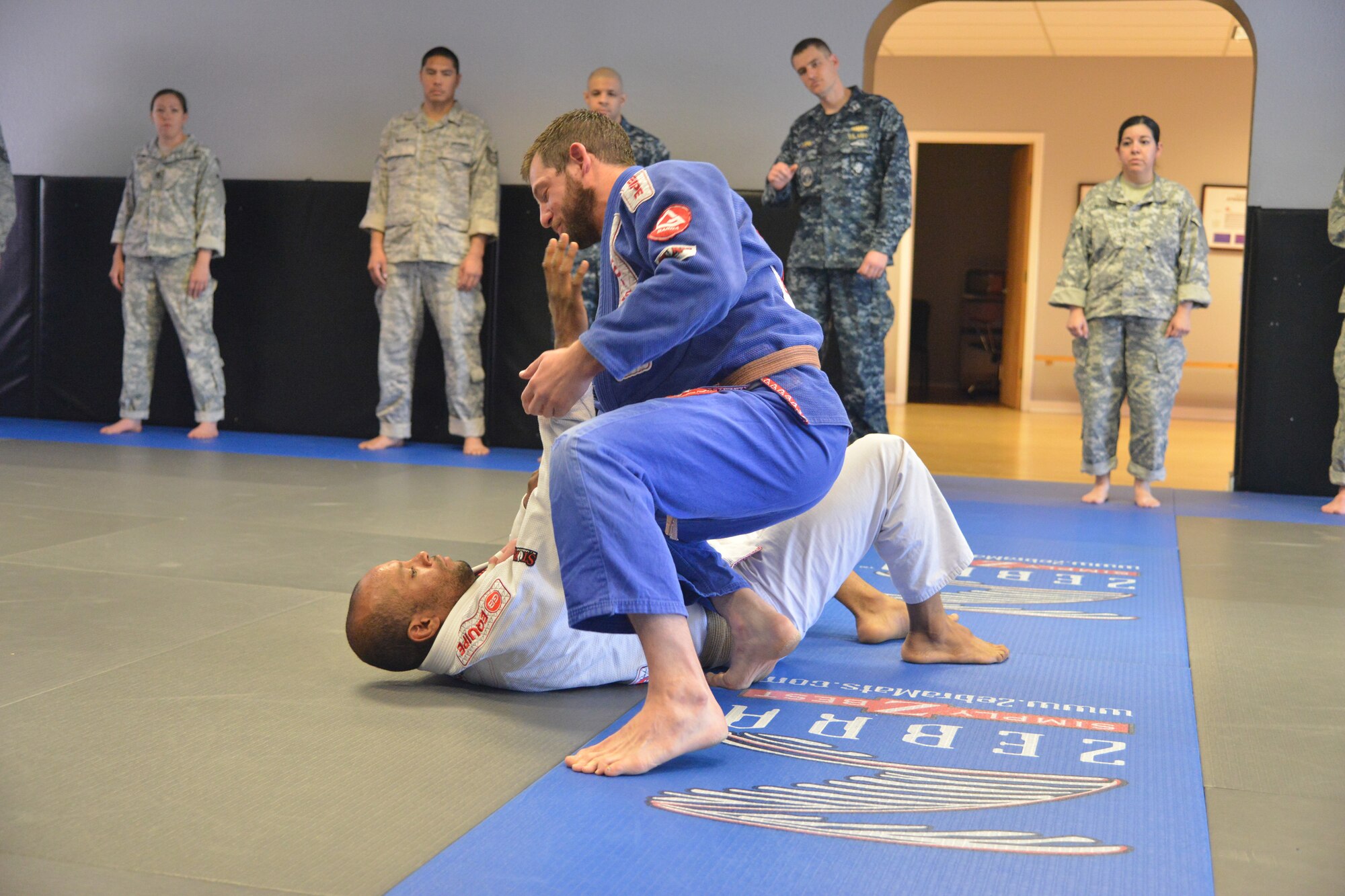 Brazilian Jiu-Jitsu instructor Dave Binder demonstrates a hold on Wesley King, another instructor at the dojo, as a group of Airmen, Soldiers and Sailors from the Defense Threat
Reduction Agency at Kirtland watch. (Photo by Todd Berenger)