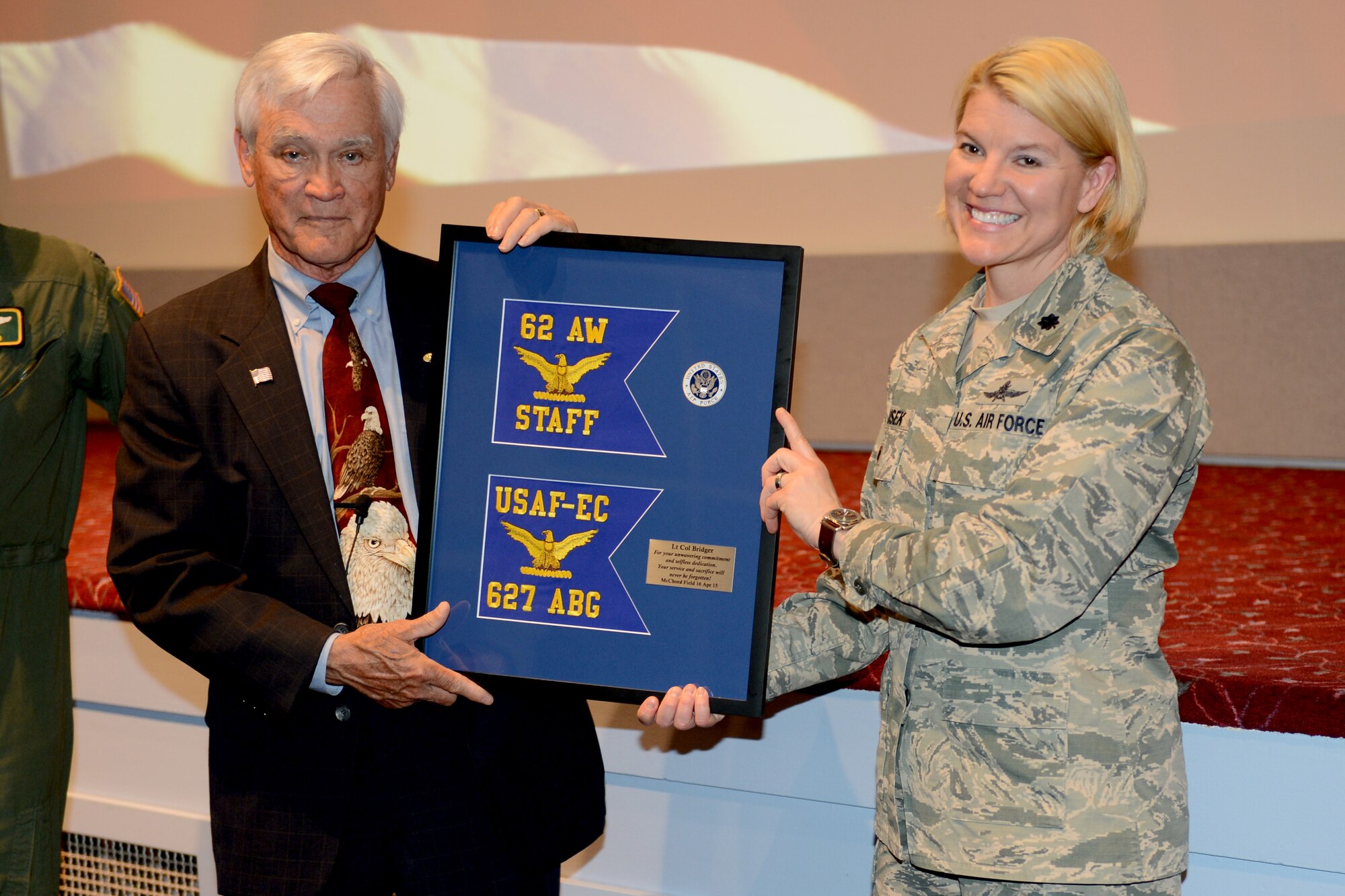 Retired Lt. Col. Barry Bridger (left), former prisoner of war, is presented with the 62nd Airlift Wing and 627th Air Base Group guidons from Lt. Col. Deborah Dusek, 627th Air Base Group deputy commander, April 16, 2015, during a presentation at Joint Base Lewis-McChord, Wash. Bridger spent six years as a POW at the “Hanoi Hilton,” Vietnam.  (U.S. Air Force photo/Airman 1st Class Keoni Chavarria)