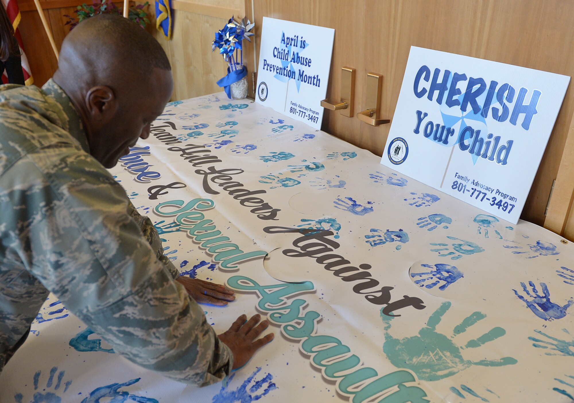 Col. Ron Jolly, 75th Air Base Wing and Installation commander places hand prints on a banner among those of other Team Hill leaders who pledged to support the fight against child abuse and sexual assault during prevention month activities here. (U.S. Air Force/Alex R. Lloyd)