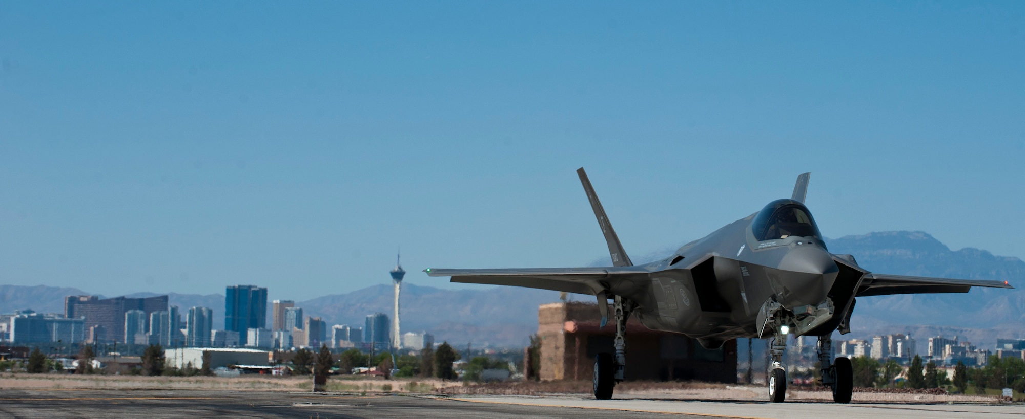 A 61st Fighter Squadron F-35 taxis prior to take off April 15, 2015 at Nellis Air Force Base, Nevada. The Las Vegas skyline is in the background. (U.S. Air Force photo by Senior Airman Thomas Spangler)