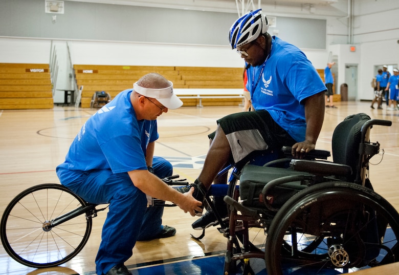 Tech. Sgt. Ryan Delaney, an Air Force Wounded Warrior mentor, guides Tremayne Maxwell, an Air Force Wounded Warrior athlete, into his straps at a wheelchair basketball session during the first day of an introductory adaptive sports and rehabilitation camp at Eglin Air Force Base, Fla., April 13.  Delaney, a flight chief with the 412th Security Forces Squadron at Edwards AFB, Calif., helped prepare approximately 45 participants in the week-long camp and training events.  (U.S. Air Force photo/Samuel King Jr.)