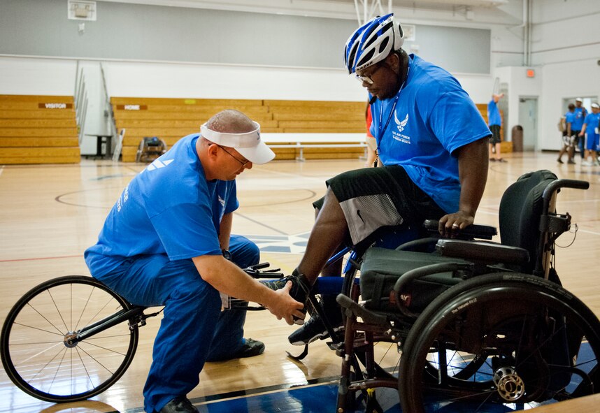 Tech. Sgt. Ryan Delaney, an Air Force Wounded Warrior mentor, guides Tremayne Maxwell, an Air Force Wounded Warrior athlete, into his straps at a wheelchair basketball session during the first day of an introductory adaptive sports and rehabilitation camp at Eglin Air Force Base, Fla., April 13.  Delaney, a flight chief with the 412th Security Forces Squadron at Edwards AFB, Calif., helped prepare approximately 45 participants in the week-long camp and training events.  (U.S. Air Force photo/Samuel King Jr.)