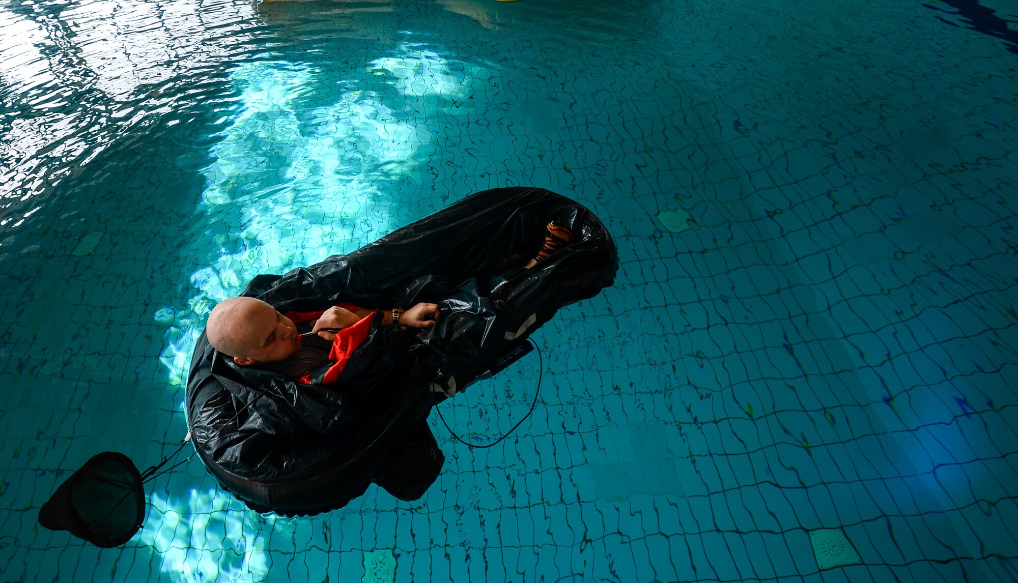 Tech. Sgt. Reid Allen, 86th Operations Support Squadron survival, evasion, resistance and escape specialist, inflates a life-raft during a water survival course April 13, 2015, at Ramstein Air Base, Germany. The course equipped service members with the skills necessary to survive in emergency water situations that can range from wild-life avoidance to dealing with heat conditions while stranded at sea.  (U.S. Air Force photo/Senior Airman Nicole Sikorski)