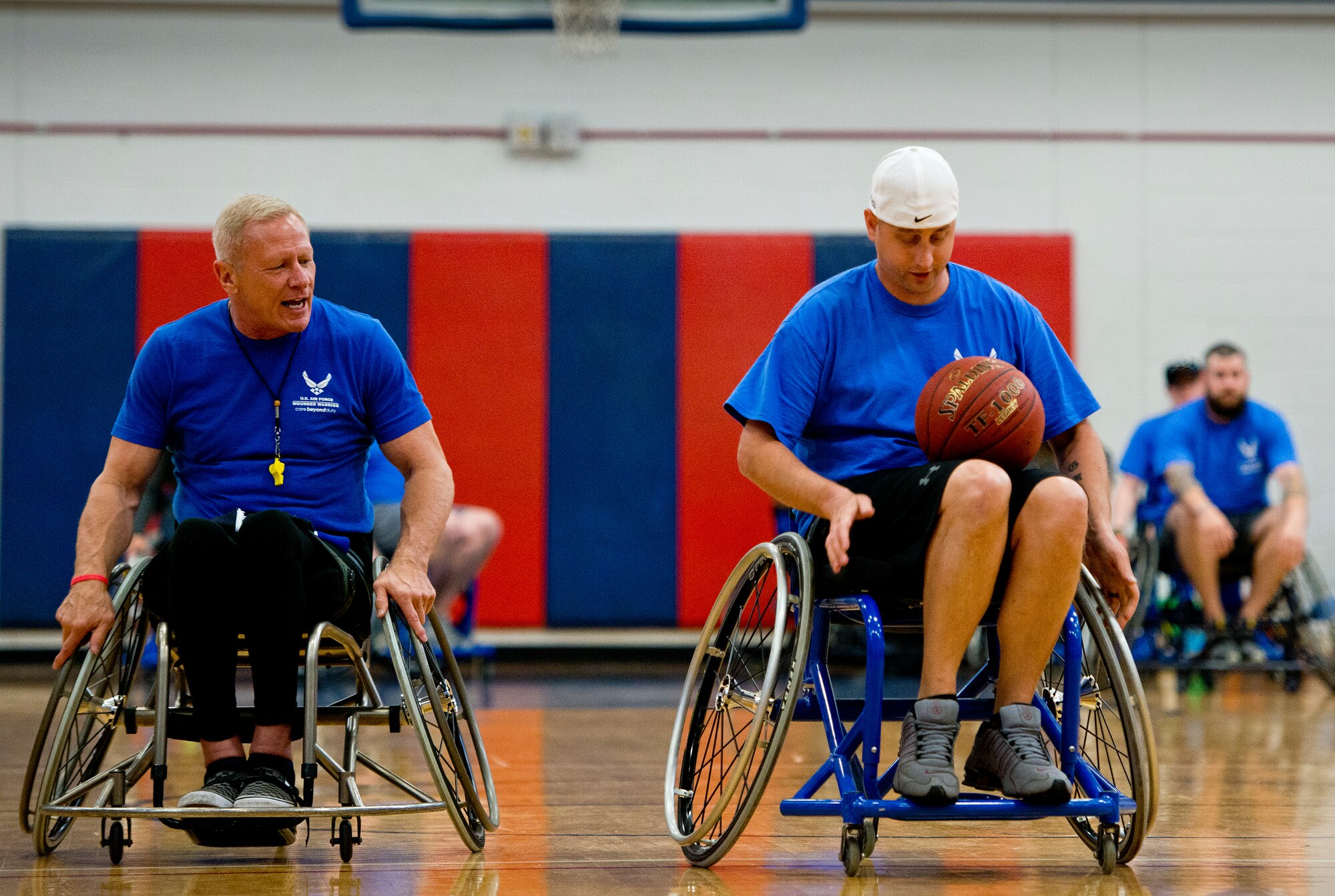 Senior Airman Chris Fugitt, a retired 96th Aircraft Maintenance Squadron Airman and an Air Force Wounded Warrior athlete, receives pointers on maneuvering a basketball with both hands from Mark Shepherd, an Air Force Wounded Warrior coach, at a wheelchair basketball session during an introductory adaptive sports and rehabilitation camp at Eglin Air Force Base, Fla., April 13.  Two years after complications from a massive stroke forced Chris to retire from the Air Force, his warrior spirit enabled him to power past a number of debilitating setbacks and attend his first camp .  (U.S. Air Force photo/Samuel King Jr.)