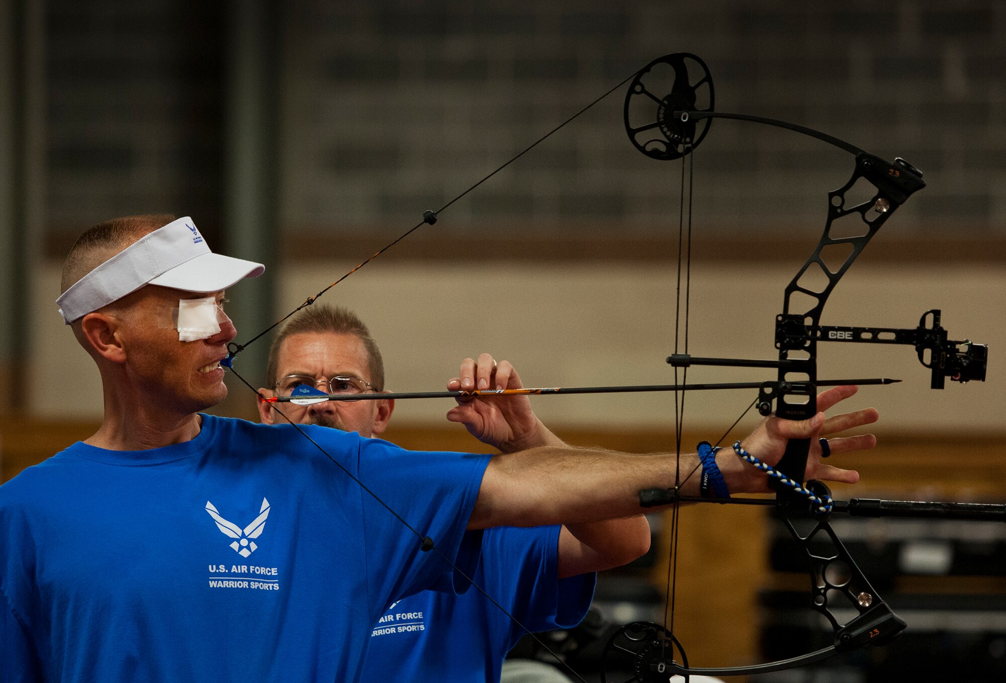 Christopher Cochrane, an Air Force Wounded Warrior athlete, gets help lining up his shot during an archery class at the fourth day of an introductory adaptive sports and rehabilitation camp at Eglin Air Force Base, Fla., April 16. The DOD’s military adaptive sports program enhances warrior recovery by engaging wounded, ill and injured service members in ongoing, daily adaptive activities, based on their interest and ability. (U.S. Air Force photo/Samuel King Jr.)