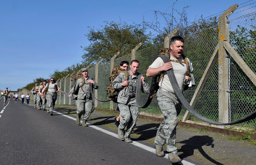 Airmen from the 100th Logistics Readiness Squadron run across the finish line as a team during a Holocaust Remembrance ruck march and monthly wing 5K run April 16, 2015, on RAF Mildenhall, England. In honor of Holocaust Remembrance Week Team Mildenhall squadrons formed teams for the ruck march to raise morale and show support. (U.S. Air Force photo by Airman 1st Class Kyla Gifford/Released)