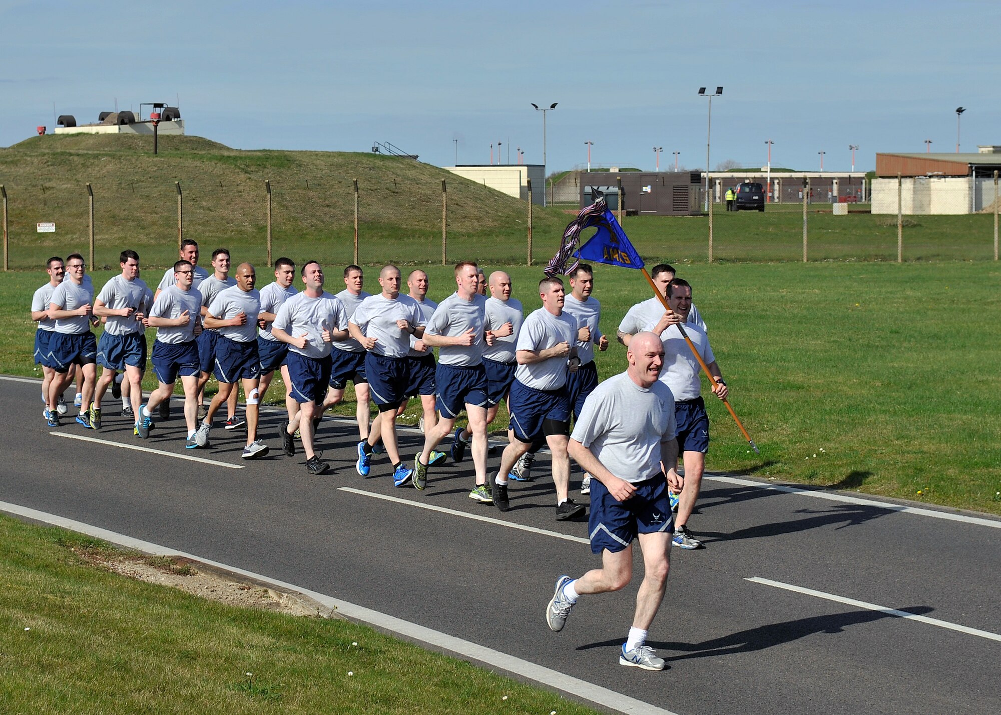 Airmen from the 100th Aircraft Maintenance Squadron run in formation during a Holocaust Remembrance ruck march and monthly wing 5K run April 16, 2015, on RAF Mildenhall, England. In honor of Holocaust Remembrance Week Team Mildenhall squadrons formed teams for the ruck march to raise morale and show support. (U.S. Air Force photo by Airman 1st Class Kyla Gifford/Released) 