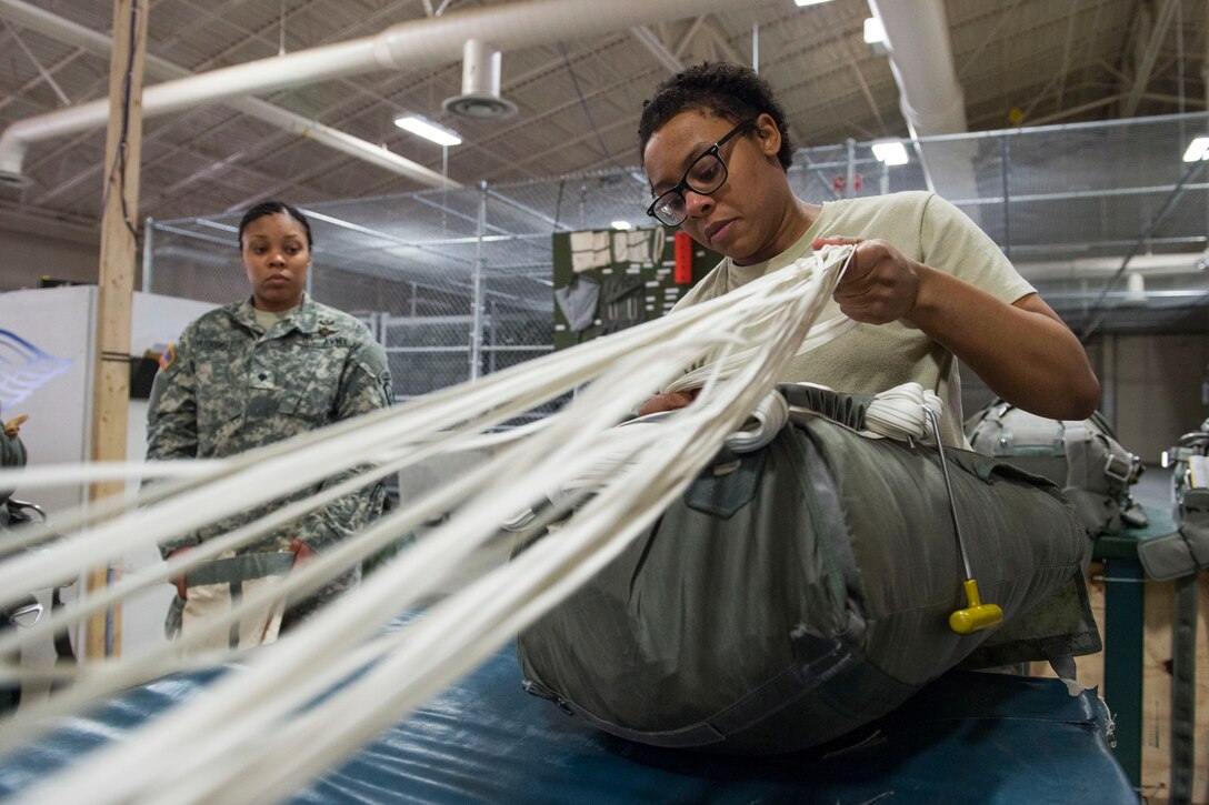 Army Spc. Brittany Williams arranges canopy cords while packing a T-11 advanced tactical parachute system at the Joint Mobility Complex on Joint Base Elmendorf-Richardson, Alaska, April 8, 2015. Williams is assigned to the 25th Infantry Division's 4th Quartermaster Company, 725th Brigade Support Battalion, 4th Brigade Combat Team, Alaska.