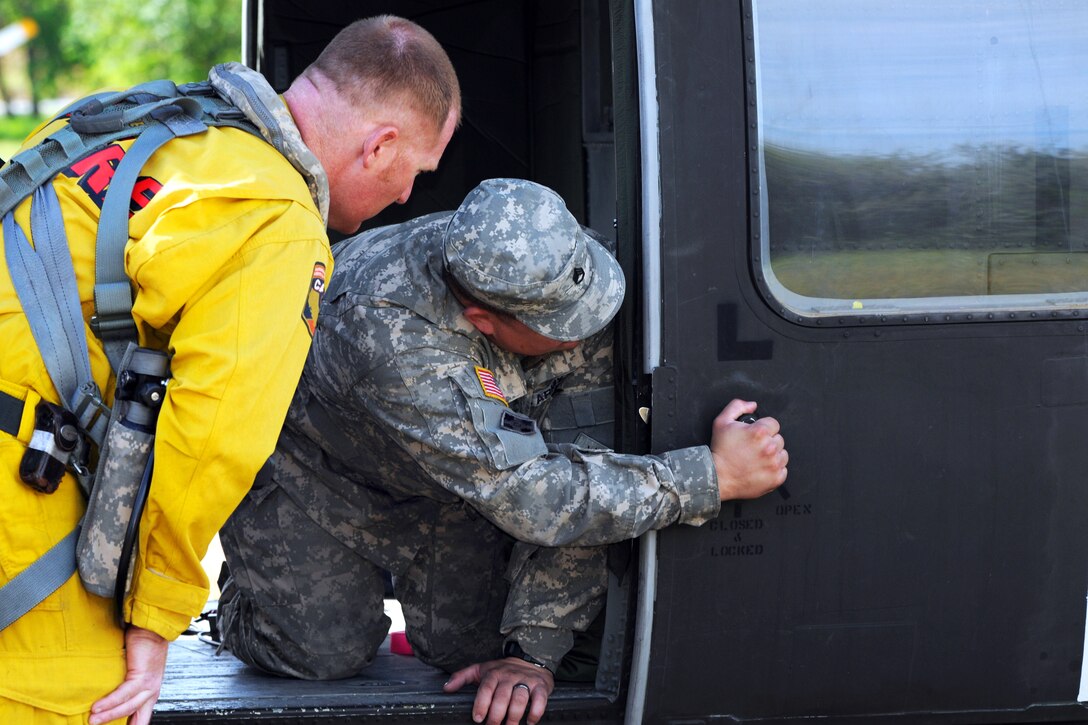 Army Staff Sgt. Anthony Poppick, right, shows Geoff Marshall, a captain with the California Department of Forestry and Fire Protection, different features on a UH-60 Black Hawk helicopter during firefighting training with California's interagency military helicopter program at the state's firefighting academy in Ione, Calif., Aprill 11, 2015. Poppick is a crew chief assigned to the California Army National Guard's Company F, 2nd Battalion, 135th General Support Aviation Battalion.