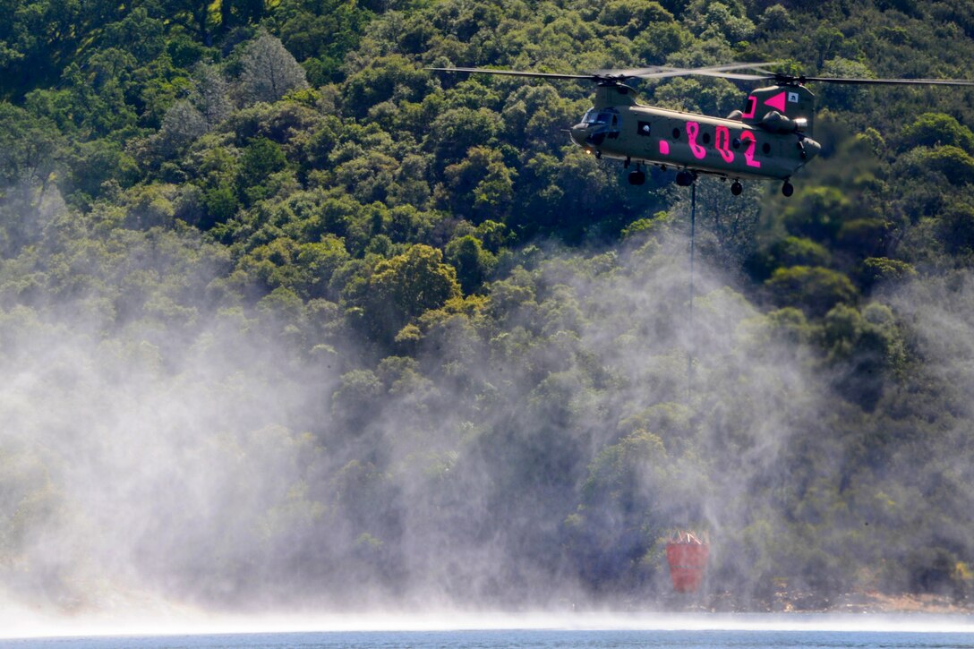 A CH-47 Chinook helicopter departs after filling a bambi bucket with water during firefighting training with California's interagency military helicopter program at the state's firefighting academy in Ione, Calif., April 11, 2015. 