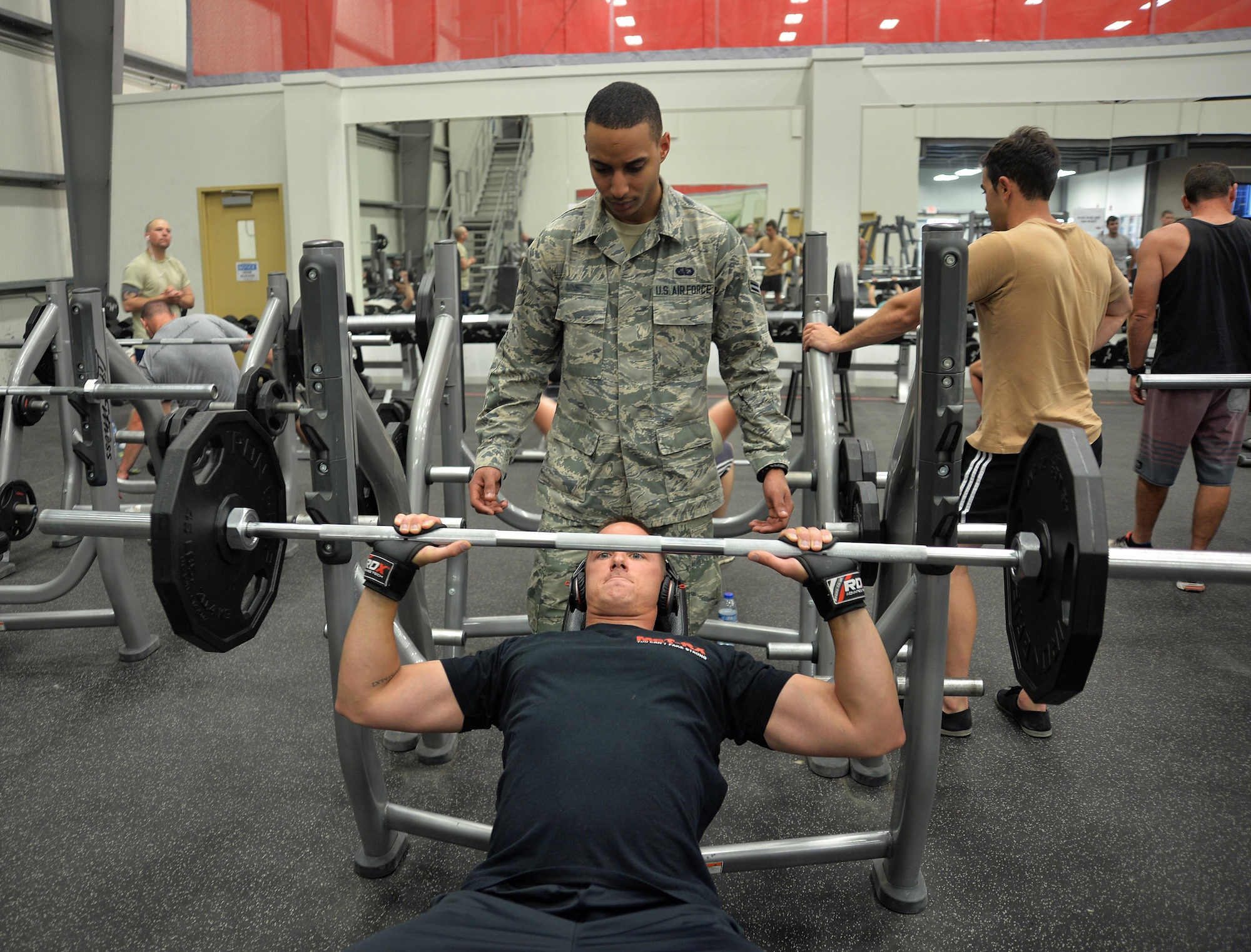 Airman First Class Josue, fitness specialist, spots Staff Sgt. Brady, heating ventilation and air conditioning craftsmen, during a lift. Airmen working in the fitness center are certified to explain and demonstrate proper conditioning procedures, weight training, and aerobic equipment techniques. (U.S. Air Force photo/Tech. Sgt. Jeff Andrejcik) 