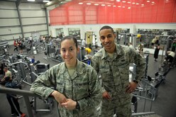 Staff Sgt. Atiana, special events coordinator, and Airman First Class Josue, fitness specialist, stand on the stairs of the fitness center at an undisclosed location in Southwest Asia April 17, 2015. Atiana and Josue’s duties include explaining and demonstrating proper conditioning procedures, weight training, and aerobic equipment techniques. (U.S. Air Force photo/Tech. Sgt. Jeff Andrejcik)