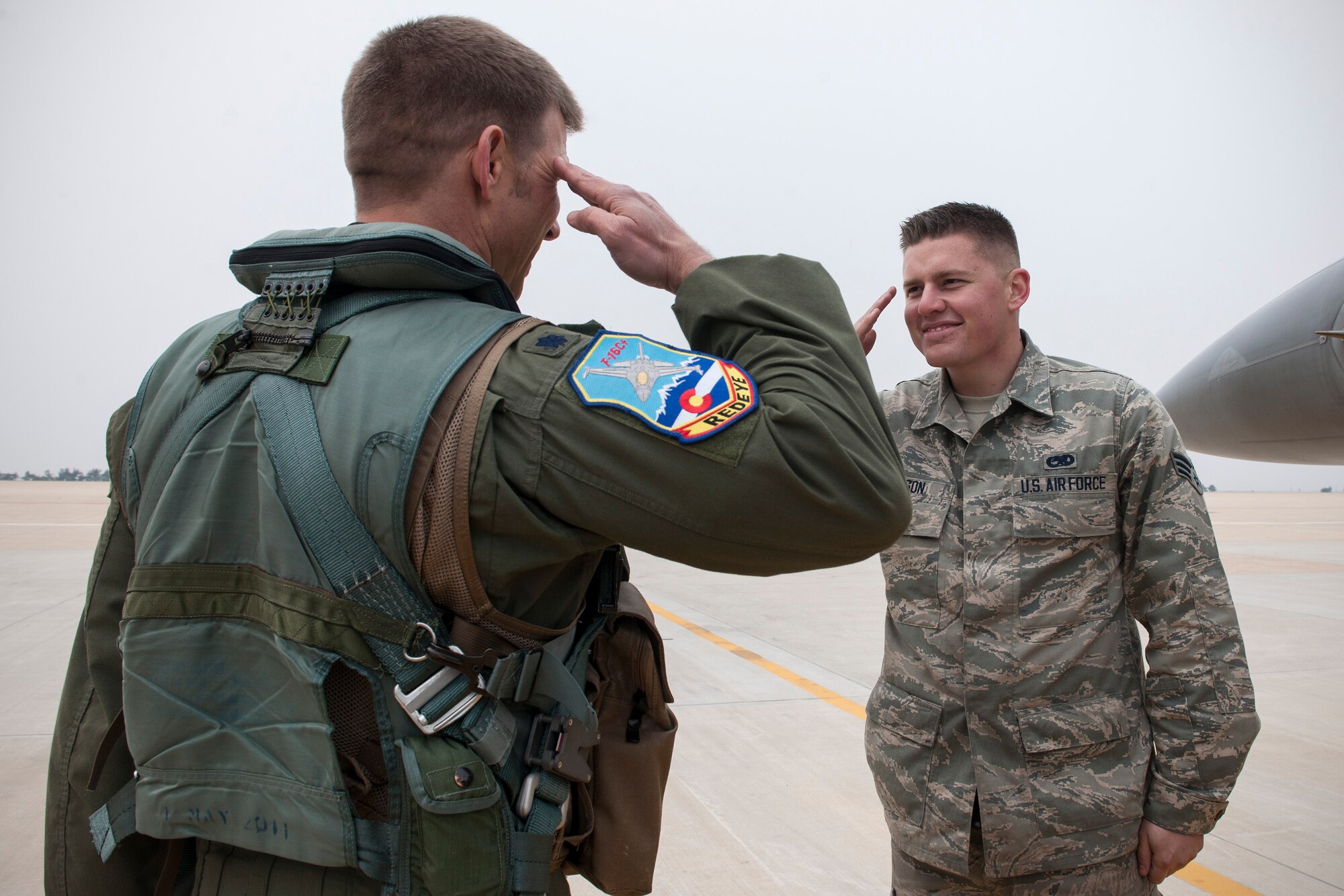 Senior Airman Mitchell Jamison, 120th Expeditionary Aircraft Maintenance Unit crew chief, salutes his father, Lt. Col. James Reeman, 120th Expeditionary Fighter Squadron F-16 Fighting Falcon pilot, April 16, 2015, at Kunsan Air Base, Republic of Korea. Reeman and Jamison, both from the 140th Wing, Colorado Air National Guard, are temporarily assigned to the Wolf Pack as part of a rotational Theater Security Package for approximately three months. (U.S. Air Force photo by Senior Airman Katrina Heikkinen/Released)