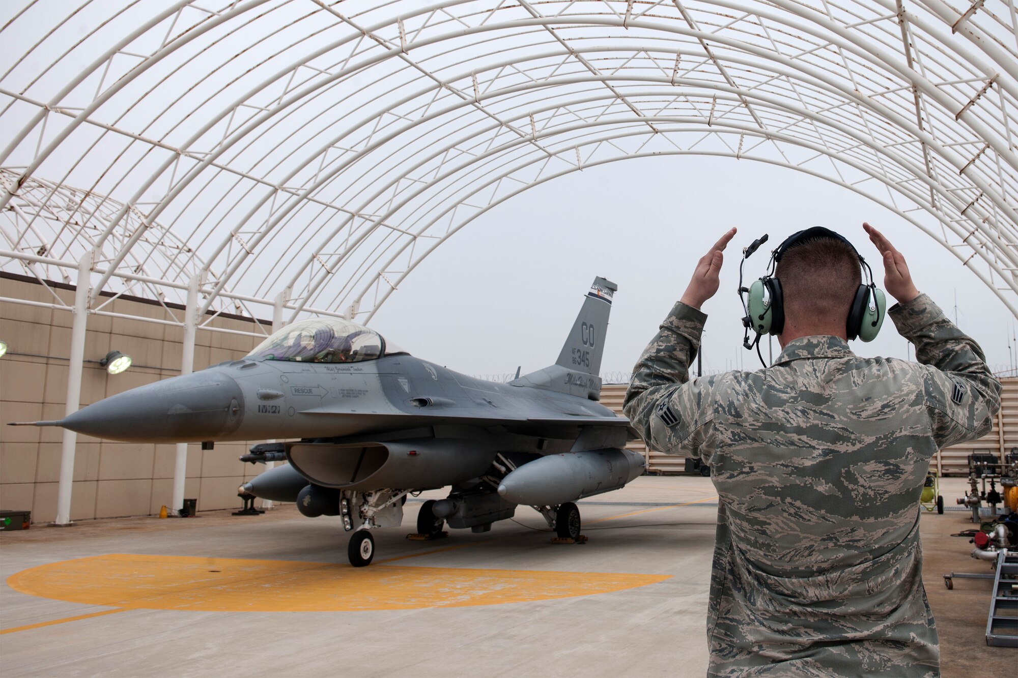 Senior Airman Mitchell Jamison, 120th Expeditionary Aircraft Maintenance Unit crew chief, marshals his father, Lt. Col. James Reeman, 120th Expeditionary Fighter Squadron F-16 Fighting Falcon pilot, April 16, 2015, at Kunsan Air Base, Republic of Korea. Following in the steps of Reeman’s father, who served 18 months in the ROK as an enlisted Marine in the 1950’s, this is both Reeman and Jamison’s first time being not only deployed together, but in the ROK. (U.S. Air Force photo by Senior Airman Katrina Heikkinen/Released)