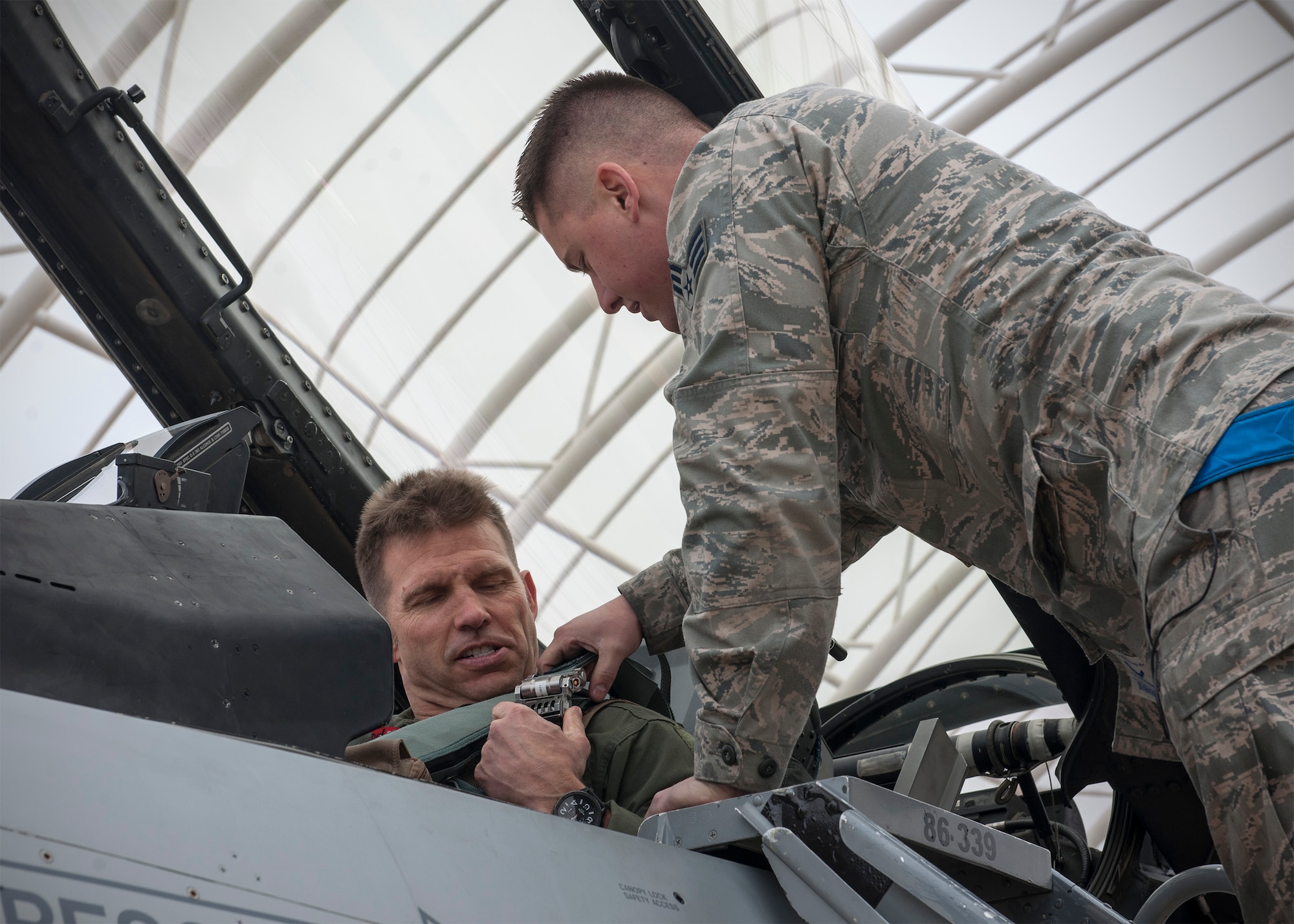 Senior Airman Mitchell Jamison, 120th Expeditionary Aircraft Maintenance Unit crew chief, secures his father, Lt. Col. James Redman, 120th Expeditionary Fighter Squadron F-16 Fighting Falcon pilot, into his jet April 16, 2015, at Kunsan Air Base, Republic of Korea. Reeman, Jamison and more than 200 Colorado Guardsmen are temporarily assigned to the Wolf Pack to augment and support active-duty Airmen as part of a rotational Theater Security Package. (U.S. Air Force photo by Senior Airman Katrina Heikkinen/Released)