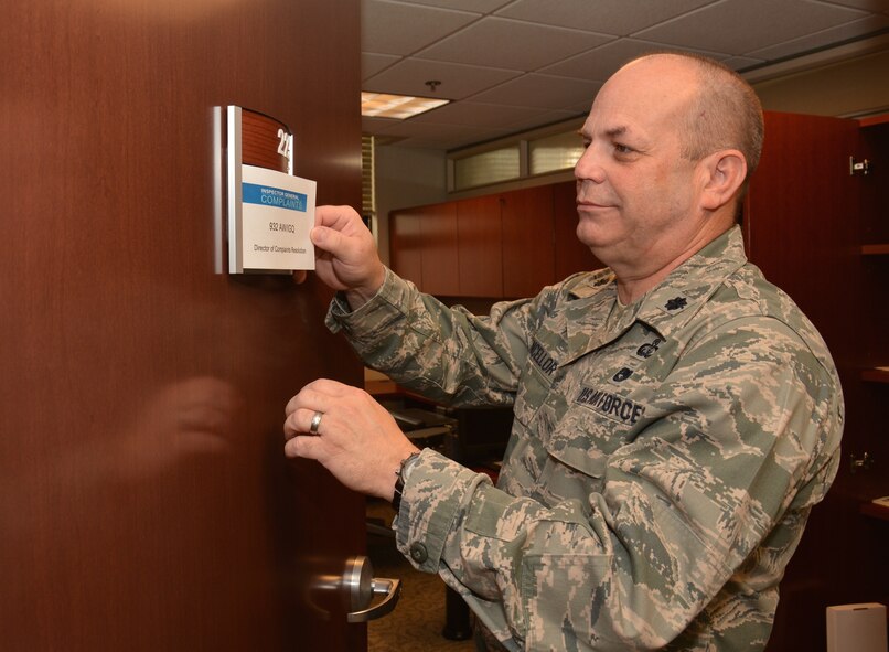 Lt. Col. Andrew Chancellor, 932nd director of complaints resolution, places the signage on the door to his new office.  Colonel Chancellor swapped offices with the wing historian, and is now located in room 223 of Wing Headquarters. (U.S. Air Force photo/ Staff Sgt. Amber Hodges)