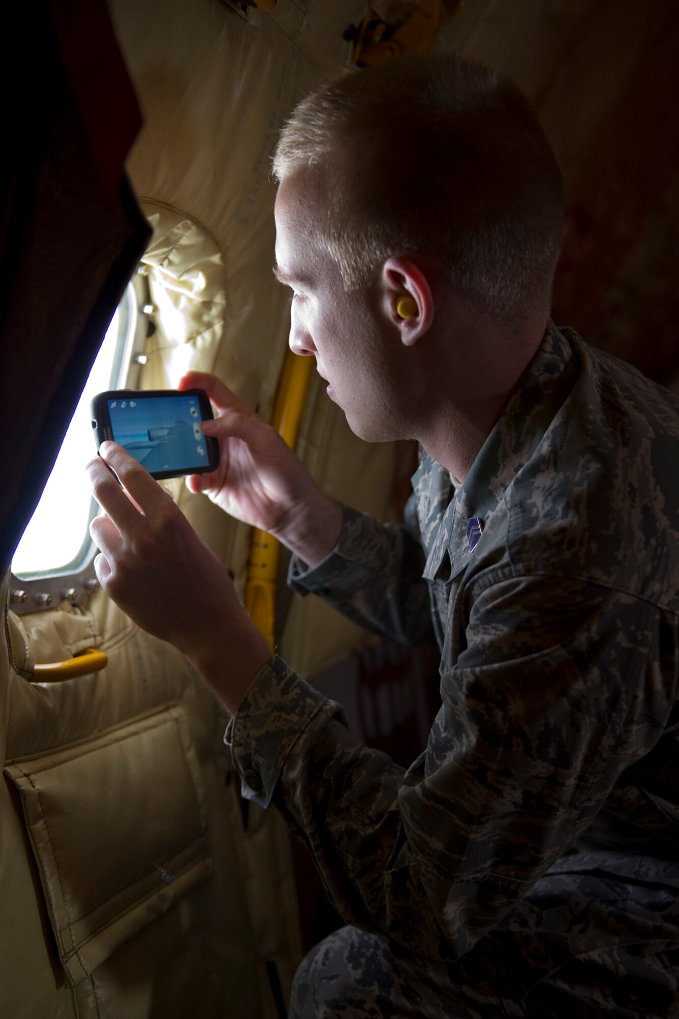 Walker Carlson, University of Notre Dame Air Force ROTC Detachment 225 cadet, uses his cell phone during an orientation flight on a 434th Air Refueling Wing KC-135 Stratotanker to take a photo of the aircrafts wing after departing Grissom Air Reserve Base, Ind., April 1, 2015.  During the flight 20 cadets and 6 midshipmen observed the refueling of a C-17 Globemaster III and an A-10 Thunderbolt II. (U.S. Air Force photo/Tech. Sgt. Benjamin Mota)