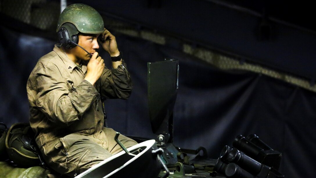 A Marine with 3rd Platoon, Alpha Company, 2nd Assault Amphibian Battalion checks the communication abilities between Marines before leaving the well-deck of the multipurpose amphibious assault ship USS Kearsarge (LHD-3) April 13, 2015. The platoon used amphibious assault vehicles to transport Marines from 1st Battalion, 6th Marine Regiment in support of a ship-to-shore exercise off the coast of Onslow Beach, Camp Lejeune, N.C. 