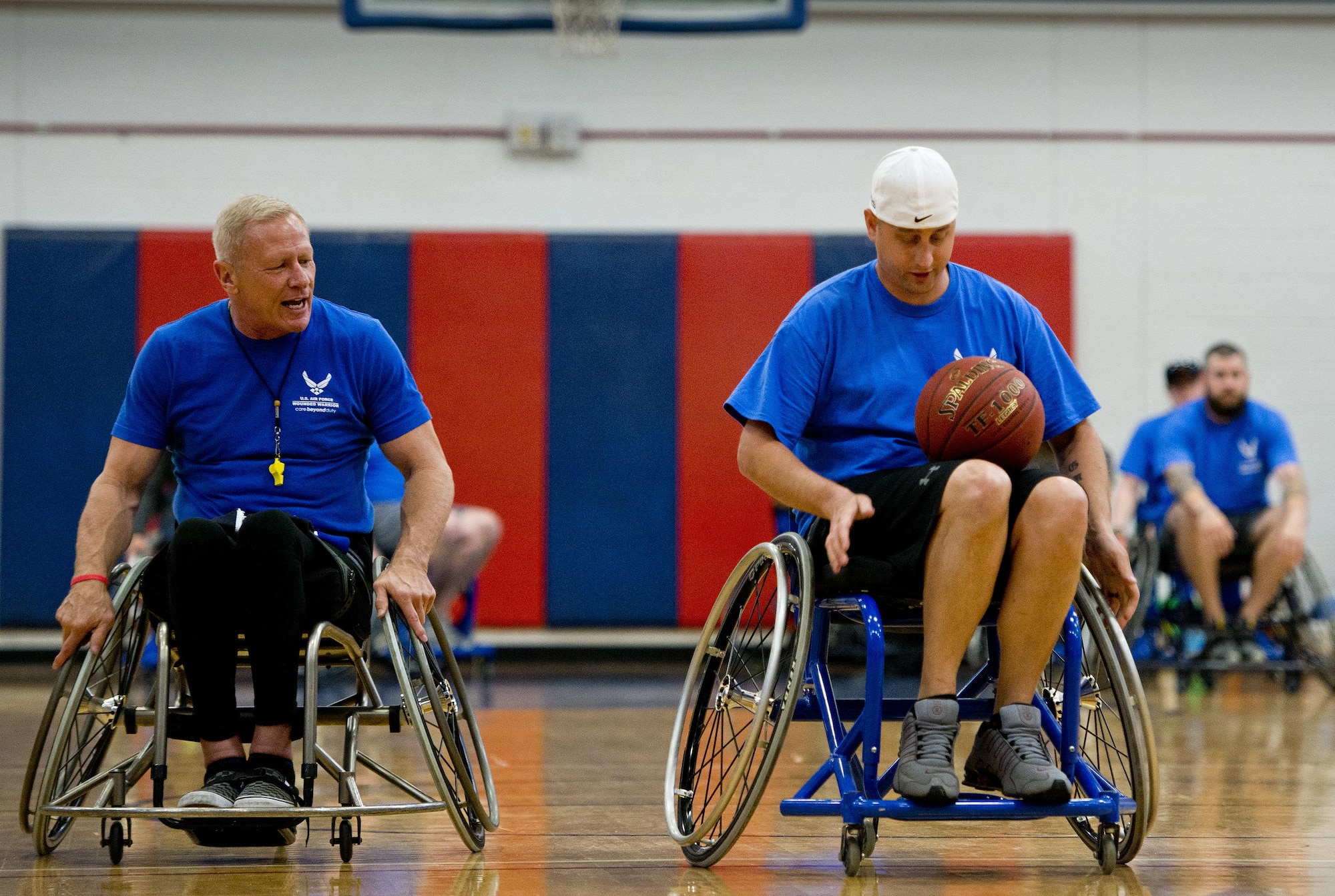 Senior Airman Chris Fugitt, a retired 96th Aircraft Maintenance Squadron Airman and an Air Force wounded warrior athlete, receives pointers on maneuvering a basketball with both hands from Mark Shepherd, an Air Force wounded warrior coach, at a wheelchair basketball session during an introductory adaptive sports and rehabilitation camp at Eglin Air Force Base, Fla., April 13, 2015. Two years after complications from a massive stroke forced Fugitt to retire from the Air Force, his warrior spirit enabled him to power past a number of debilitating setbacks and attend his first camp. (U.S. Air Force photo/Samuel King Jr.)