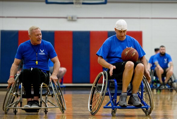 Senior Airman Chris Fugitt, a retired 96th Aircraft Maintenance Squadron Airman and an Air Force wounded warrior athlete, receives pointers on maneuvering a basketball with both hands from Mark Shepherd, an Air Force wounded warrior coach, at a wheelchair basketball session during an introductory adaptive sports and rehabilitation camp at Eglin Air Force Base, Fla., April 13, 2015. Two years after complications from a massive stroke forced Fugitt to retire from the Air Force, his warrior spirit enabled him to power past a number of debilitating setbacks and attend his first camp. (U.S. Air Force photo/Samuel King Jr.)