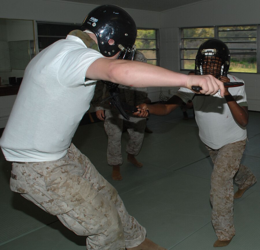 Cpl. Ariana Atterberry (right) lunges forward with her simulated knife outlined with red lipstick and thrusts it into Sgt. Nathan Phelps’ major organ, leaving a smeared, faux blood stain on his white T-shirt, during Marine Corps Martial Arts Program knife fighting techniques class at Marine Corps Logistics Base Albany’s dojo, recently.
