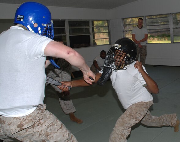 Cpl. Ariana Atterberry (right) lunges forward with her simulated knife outlined with red lipstick and thrusts it into Sgt. Nathan Phelps’ major organ, leaving a smeared, faux blood stain on his white T-shirt, during Marine Corps Martial Arts Program knife fighting techniques class at Marine Corps Logistics Base Albany’s dojo, recently.