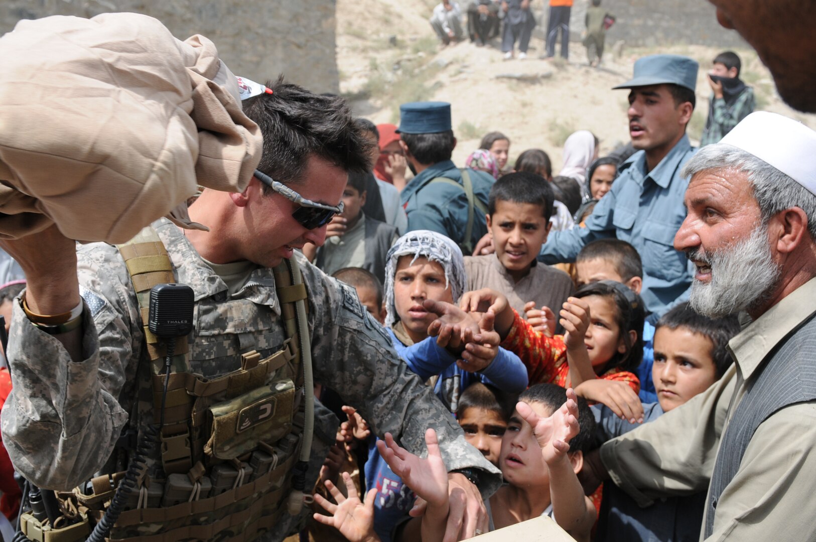 Staff Sgt. Joshua Smith, squad leader for Police Mentor Team 7, Bravo Battery, 1st Battalion, 101st Field Artillery of the Vermont Army National Guard, grabs a bundle of clothing for a child from the Shohadayi Salehin village during a humanitarian aid drop for needy school kids in one of the city's poorest neighborhoods in Kabul, Afghanistan Sept. 6, 2010. The Vermont Guard unit partnered with Afghan National Police to help hand out school supplies and demonstrate a goodwill initiative for the people they are helping to protect.