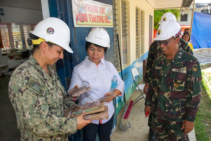 In this file photo, U.S. Navy Lt. Cmdr. Catherine Eyrich, left, shows a meal, ready to eat, to the mayor of Tapaz municipality, Rosmarie F. Gardose, center, during exercise Balikatan 2015. Eyrich is commander of the Combined-Joint Civil-Military Operations Task Force on Panay. 