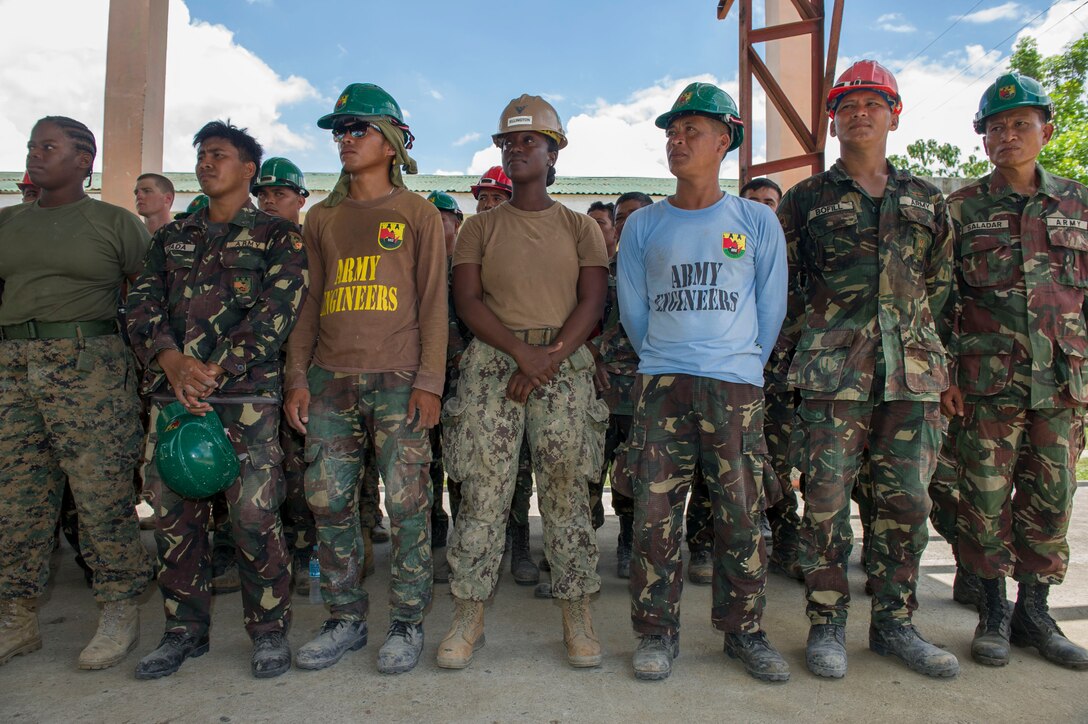 U.S. Navy Builder 3rd Class Mishonne Ellington, center, assigned to Naval Mobile Construction Battalion 5, stands shoulder-to- shoulder in formation with Armed Forces of the Philippines Army engineers, assigned to the 552nd Engineer Construction Battalion, during an all hands call with Capt. James G. Meyer, Combined-Joint Civil-Military Operations Task Force commander for Balikatan 2015, at Don Joaquin Artuz Memorial Elementary School in Tapaz, Philippines, during the exercise, April 16. The engineers, along with U.S. Marines from the 9th Engineer Support Battalion, are constructing two classrooms at the school. Balikatan, which means “shoulder to shoulder” in Filipino, is an annual bilateral training exercise aimed at improving the ability of Philippine and U.S. military forces to work together during planning, contingency, humanitarian assistance and disaster relief operations.