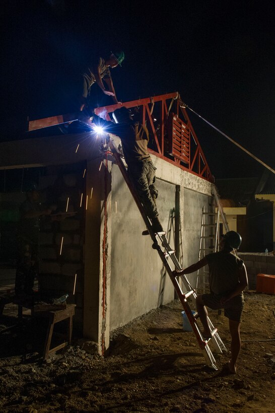 Armed Force of the Philippines Army Engineers, assigned to the 552nd Engineer Construction Battalion, observe U.S. Navy Steelworker 2nd Class Juan Lopez, assigned to Naval Mobile Construction Battalion 5, weld a roof truss at Don Joaquin Artuz Memorial Elementary School in Tapaz, Philippines, during Balikatan 2015, April 16. The engineers, along with U.S. Marines from the 9th Engineer Support Battalion, are part of the Joint Civil-Military Operations Task Force on the island of Panay, which is constructing two classrooms at the school. Balikatan, which means “shoulder to shoulder” in Filipino, is an annual bilateral training exercise aimed at improving the ability of Philippine and U.S. military forces to work together during planning, contingency, humanitarian assistance and disaster relief operations. (U.S. Navy photo by Chief Mass Communication Specialist Lowell Whitman/Released)