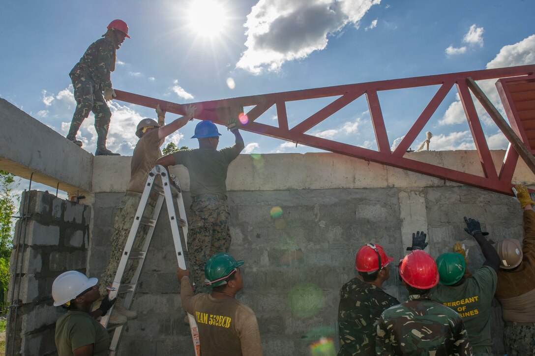 U.S. Marine engineers, assigned to the 9th Engineer Support Battalion, U.S. Navy Seabees, assigned to Naval Mobile Construction Battalion 5, and Armed Forces of the Philippines Army engineers from the 552nd Engineer Construction Battalion, lift a roof truss for placement at Don Joaquin Artuz Memorial Elementary School in Tapaz, Philippines, during Balikatan 2015, April 16. The engineers are part of the Joint Civil-Military Operations Task Force on the island of Panay constructing two
classrooms at the school. Balikatan, which means “shoulder to shoulder” in Filipino, is an annual bilateral training exercise aimed at improving the ability of Philippine and U.S. military forces to work together during planning, contingency, humanitarian assistance and disaster relief operations.
