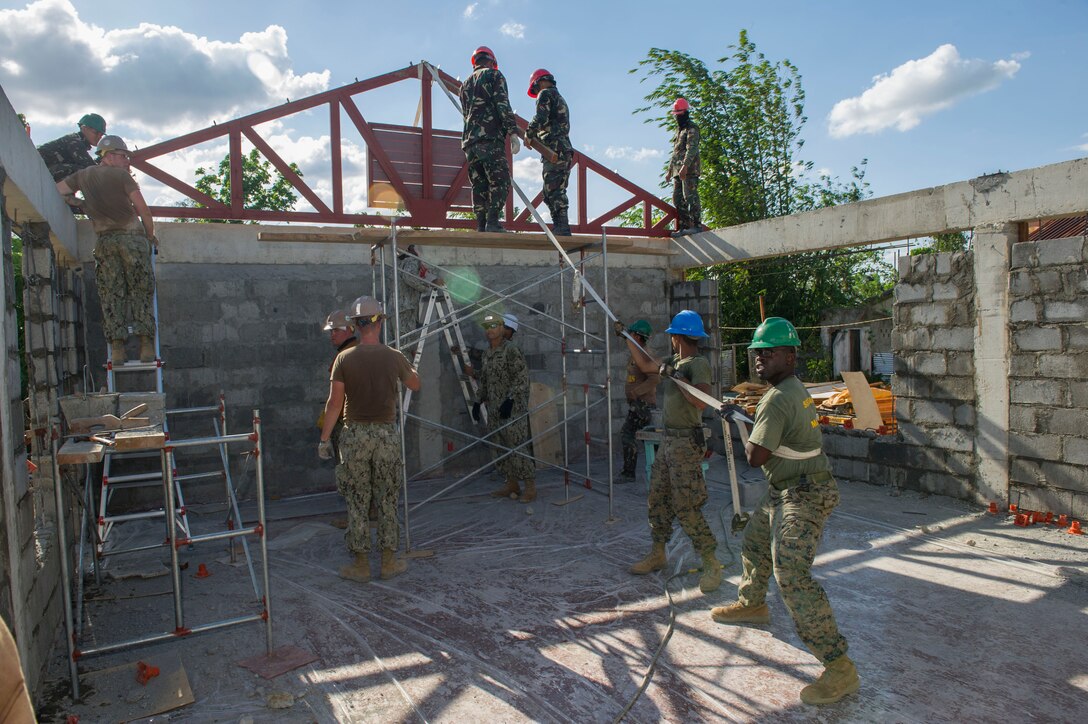 U.S. Marine engineers, assigned to the 9th Engineer Support Battalion, U.S. Navy Seabees, assigned to Naval Mobile Construction Battalion 5, and Armed Forces of the Philippines Army engineers from the 552nd Engineer Construction Battalion, move a roof truss for placement at Don Joaquin Artuz Memorial Elementary School in Tapaz, Philippines, during Balikatan 2015, April 16. The engineers are part of the Joint Civil-Military Operations Task Force on the island of Panay constructing two classrooms at the school. Balikatan, which means “shoulder to shoulder” in Filipino, is an annual bilateral training exercise aimed at improving the ability of Philippine and U.S. military forces to work together during planning, contingency, humanitarian assistance and disaster relief operations. 