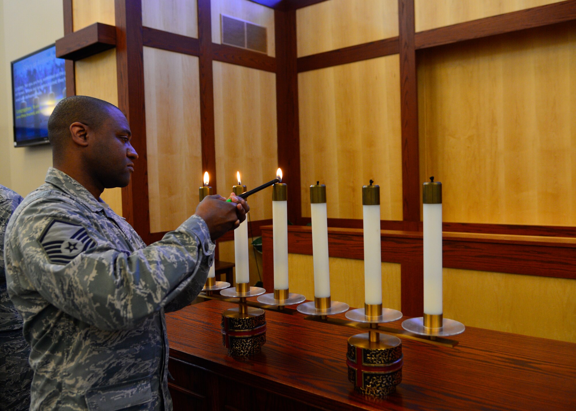 Master Sgt. Richard Matthews, Jr., 436th Medical Operations Squadron Mental Health flight chief, lights a candle during the Holocaust Remembrance Observance April 16, 2015, at Chapel 1 on Dover Air Force Base, Del. The six candles represented the six million Jews that lost their lives during the Holocaust. (U.S. Air Force photo/Airman 1st Class William Johnson)