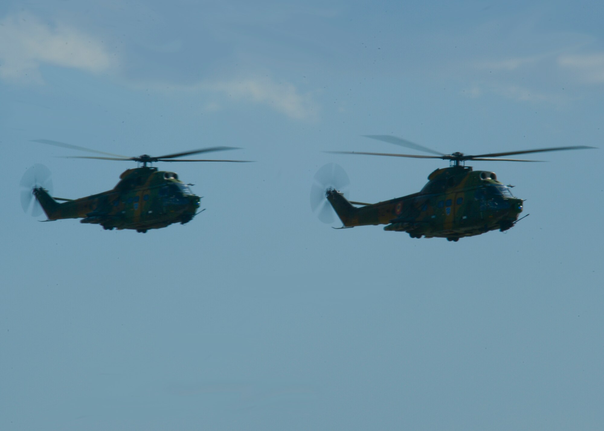 Two Romanian air force Puma helicopters assigned to the 71st Air Base fly above the flightline at Campia Turzii, Romania, April 16, 2015. The U.S. and Romanian air forces will conduct training aimed to strengthen interoperability and demonstrate the countries' shared commitment to the security and stability of Europe. (U.S. Air Force photo by Staff Sgt. Joe W. McFadden/Released)