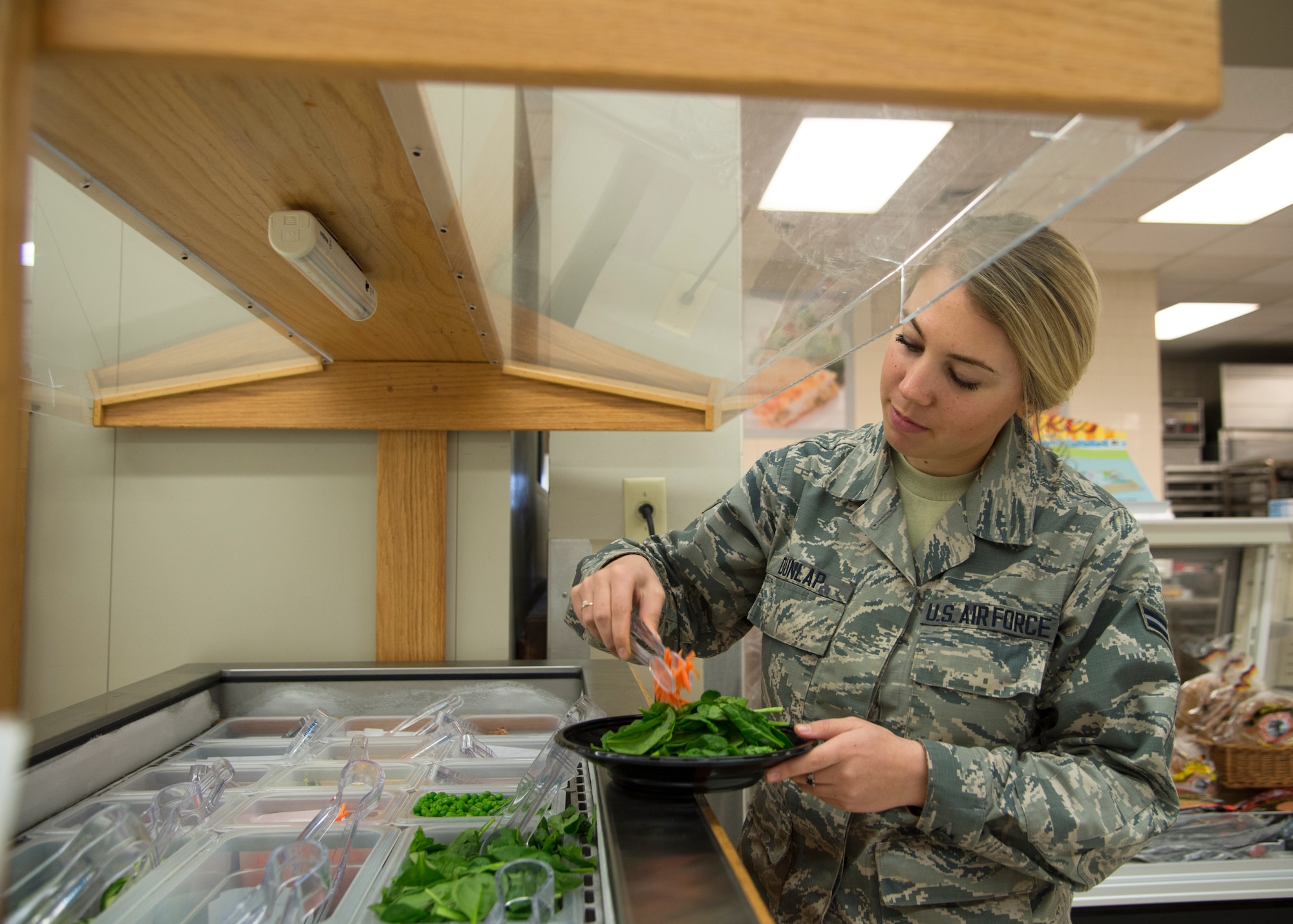 Airman 1st Class Lauren Dunlap, 436th Communications Squadron client systems technician, prepares a salad April 17, 2015, at the Commissary on Dover Air Force Base, Del. The Commissary installed a new salad bar as a lunch option for Airmen while the Patterson Dining Facility is closed during the Food Transformation Initiative. (U.S. Air Force photo/Airman 1st Class William Johnson)