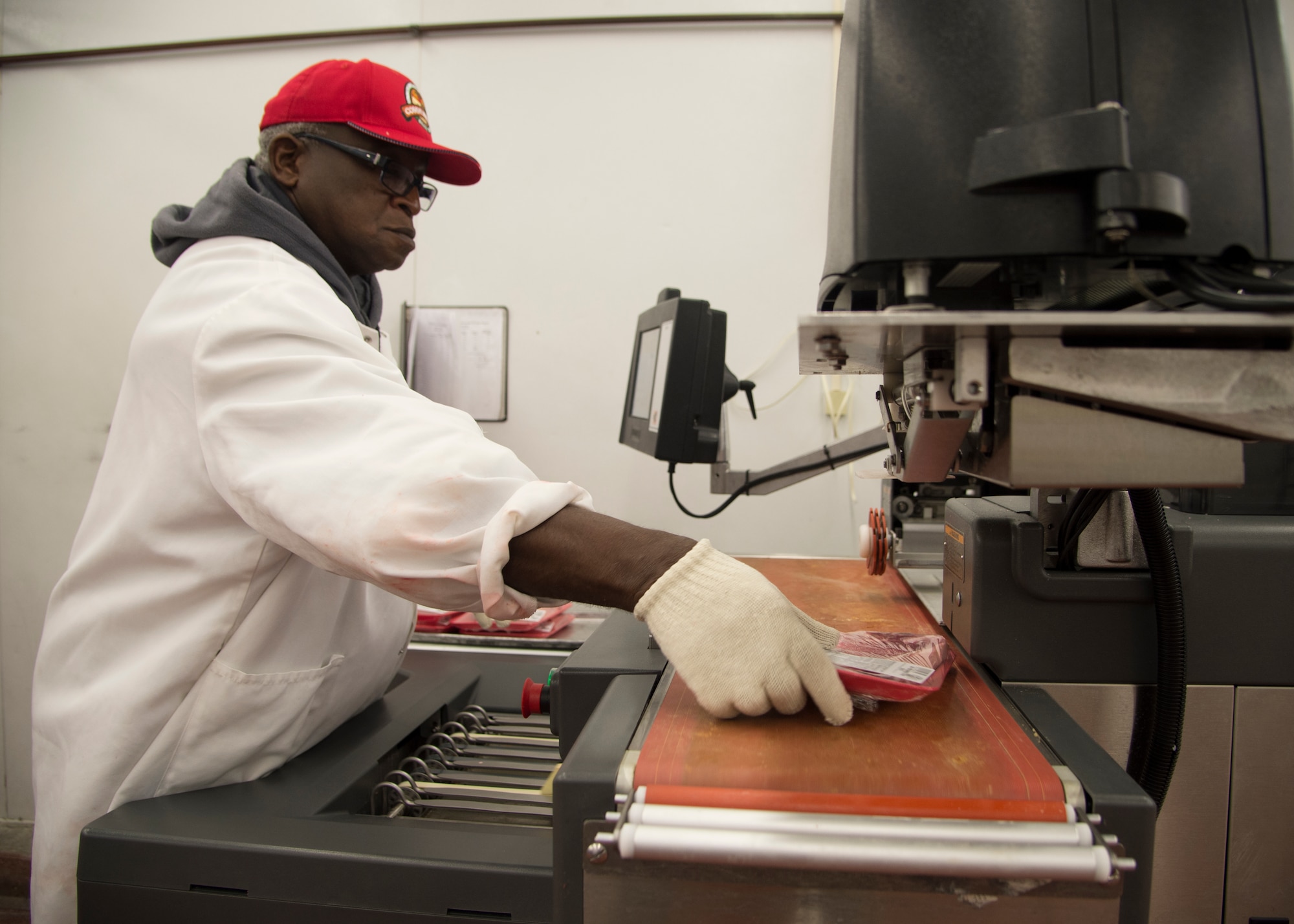 Robert Gainey, Dover Air Force Base Commissary meat cutter, grabs an individually wrapped T-bone steak off of a Hobart wrapping machine April 17, 2015, at the Commissary on Dover AFB, Del. Airmen can buy individual portions of steak, pork and chicken from the commissary meat department. (U.S. Air Force photo/Airman 1st Class William Johnson) 