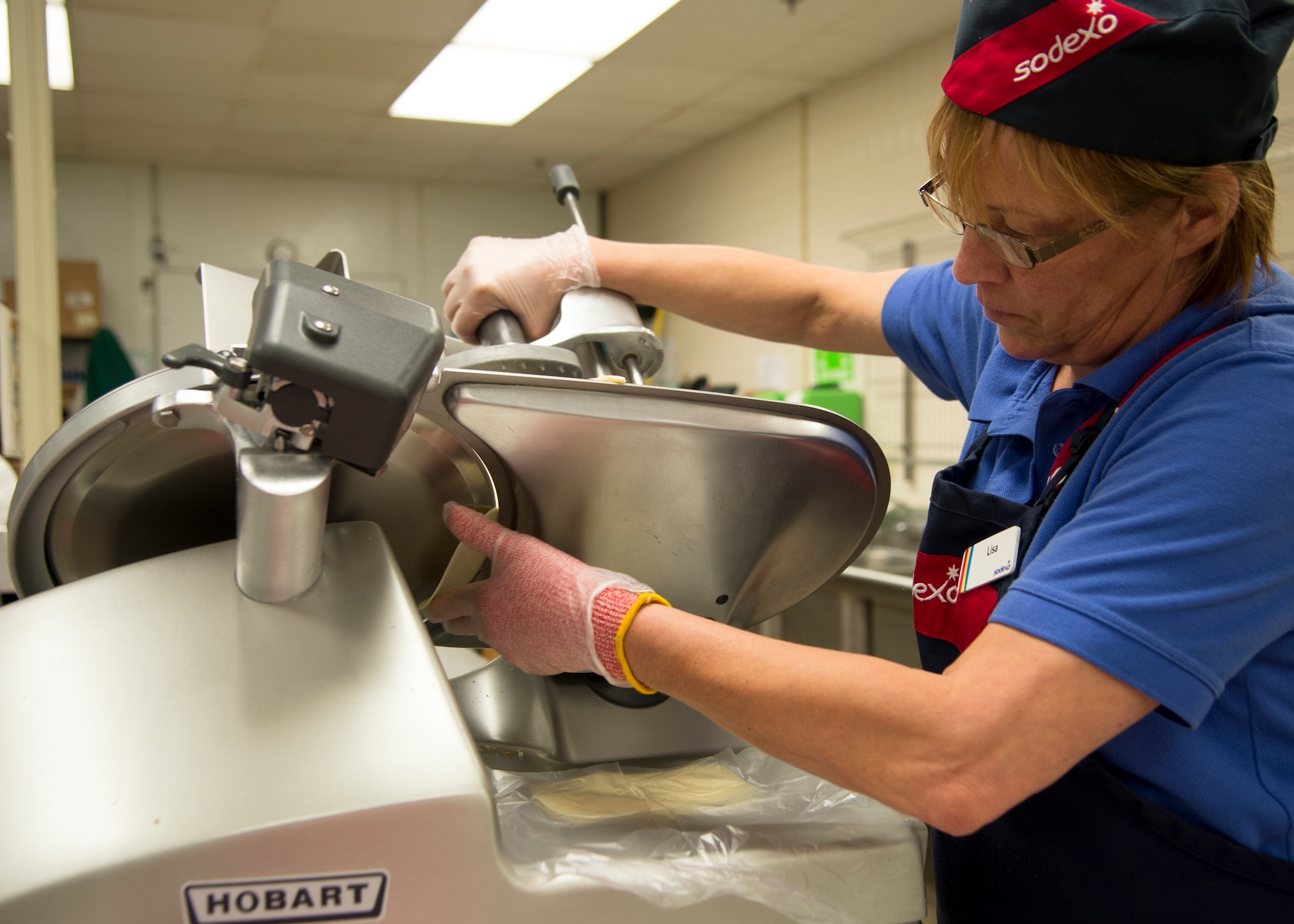 Lisa Chandonnet , Dover Air Force Base Commissary deli clerk, slices cheese for an Airman April 17, 2015, at the Commissary on Dover AFB, Del. Individual servings of deli meat and cheese are available to order through the deli department along with custom made sandwiches.  (U.S. Air Force photo/Airman 1st Class William Johnson)