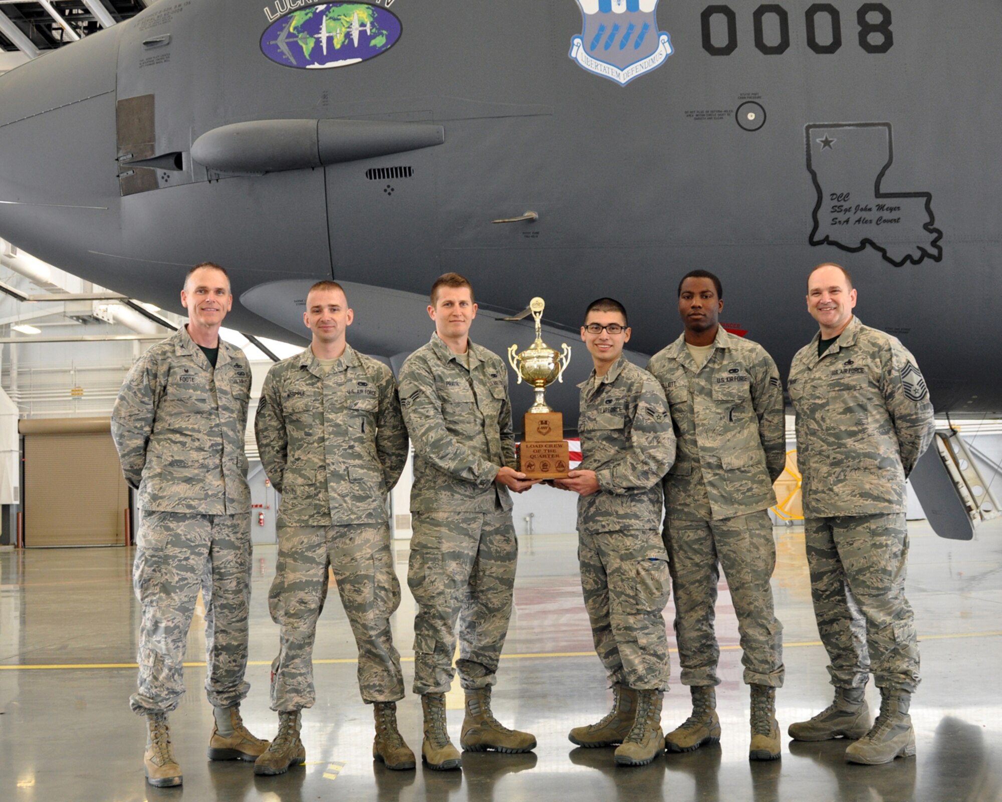 The 2nd Aircraft Maintenance Squadron Weapons Load Crew of the Quarter are presented with a trophy by 2nd Maintenance Group Commander, Col. David Foote and the 2nd Maintenance Group Superintendent, Chief Master Sgt. Steven Bush. The competition included a dress and appearance inspection, a written test, an inspection of tools and equipment, along with the timed weapons loading technical operation. (U.S. Air Force photo by Master Sgt. Laura Siebert/Released)