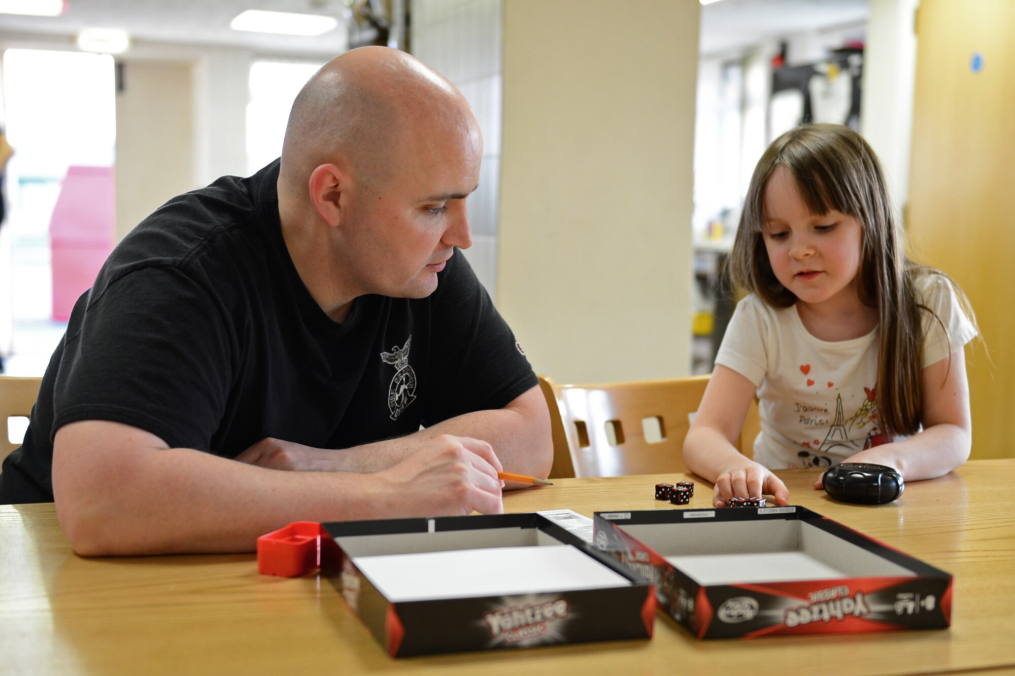 Tech. Sgt. Kevin Coughlin, 48th Civil Engineer Squadron fire station captain, plays games with his daughter, Leigha, after dinner at the Royal Air Force Lakenheath fire station, England, April 8, 2015. The station opens its doors every evening to family and friends. (U.S. Air Force photo by Airman 1st Class Erin R. Babis/Released)