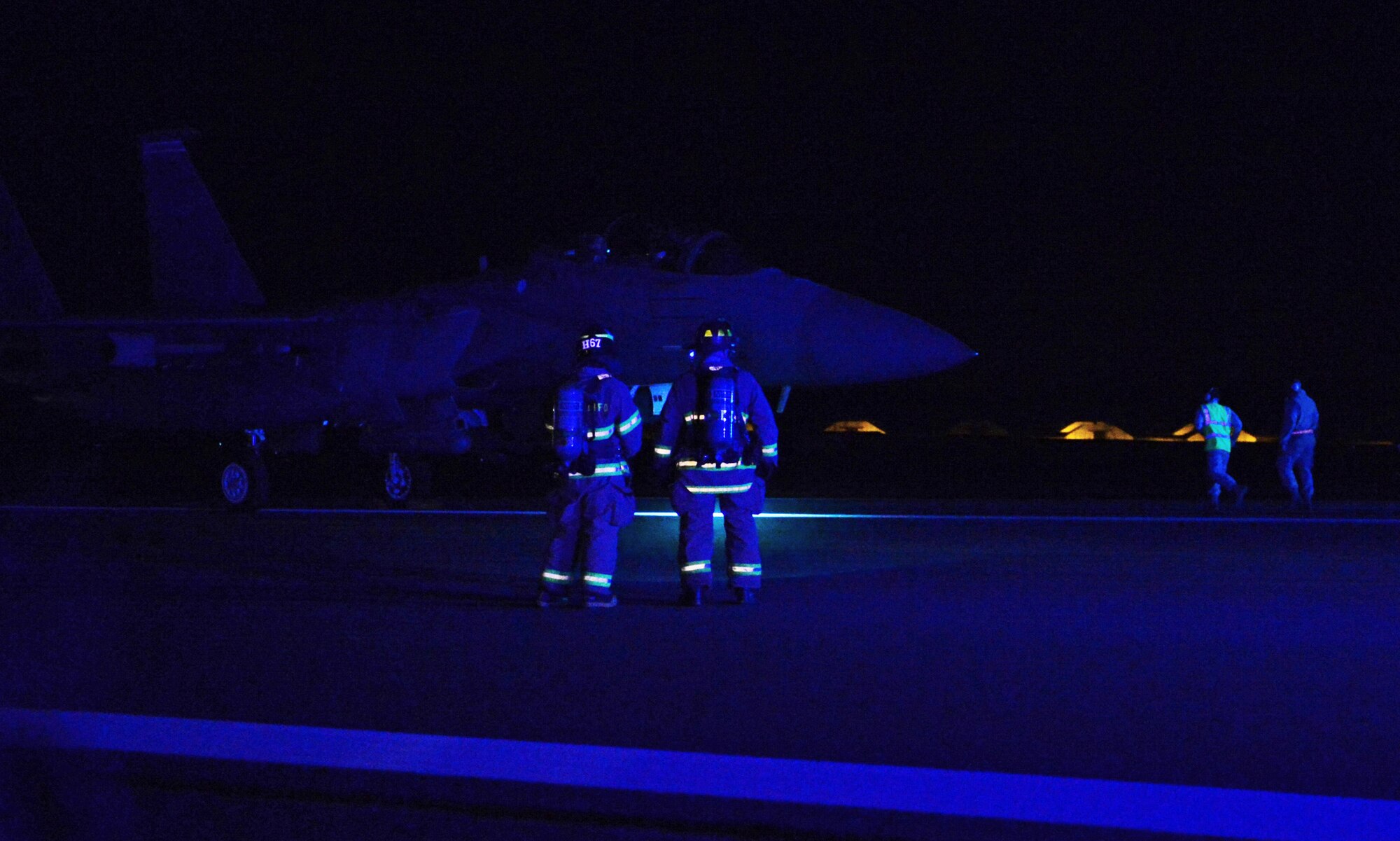 Airman 1st Class Mark Heupel, 48th Civil Engineer Squadron firefighter, and Tech. Sgt. William Strauss, 48th CES fire station captain, wait to pin and chock an F-15E Strike Eagle during a barrier engagement at Royal Air Force Lakenheath, England, April 8, 2015. Firefighters train to respond at a moment’s notice, 24 hours a day, to any emergency. (U.S. Air Force photo by Airman 1st Class Erin R. Babis/Released)