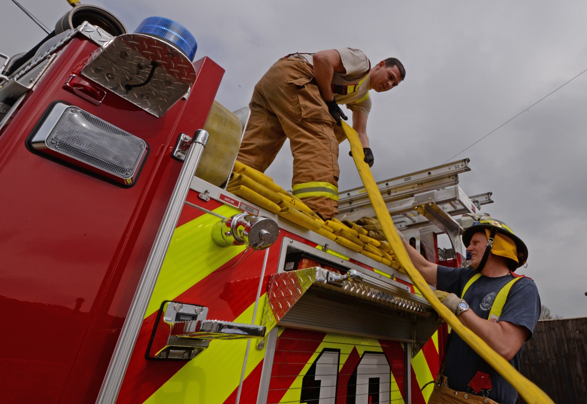 Staff Sgt. Tyler McLain, 48th Civil Engineer Squadron fire crew chief, and Kim Scotney, 48th CES driver operator, reload a hose after a simulated structure fire exercise at Royal Air Force Lakenheath, England, April 8, 2015. The 48th CES firefighters trained to remain proficient in their response to emergencies. (U.S. Air Force photo by Airman 1st Class Erin R. Babis/Released)
