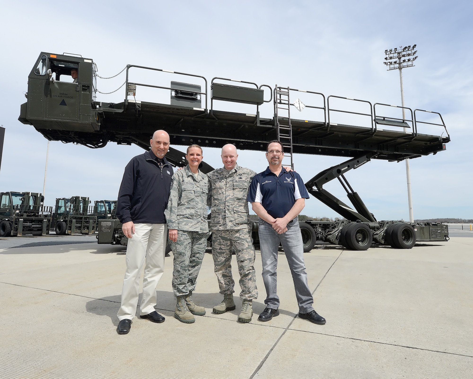 Tom Banez, 9th Airlift Squadron honorary commander, Chief Master Sgt. Sandra Scott, 436th Aerial Port Squadron chief, Lt. Col. Jarod Blecher, 436th APS commander, and John Yoho, 436th APS honorary commander pose in front of a 60K 'Tunner' cargo transport and loading vehicle during a tour of the 436th Maintenance Group April 15, 2015, on Dover Air Force Base, Del. The Air Force uses the Tunner to efficiently transport cargo to and from aircraft. (U.S. Air Force photo/Greg L. Davis)