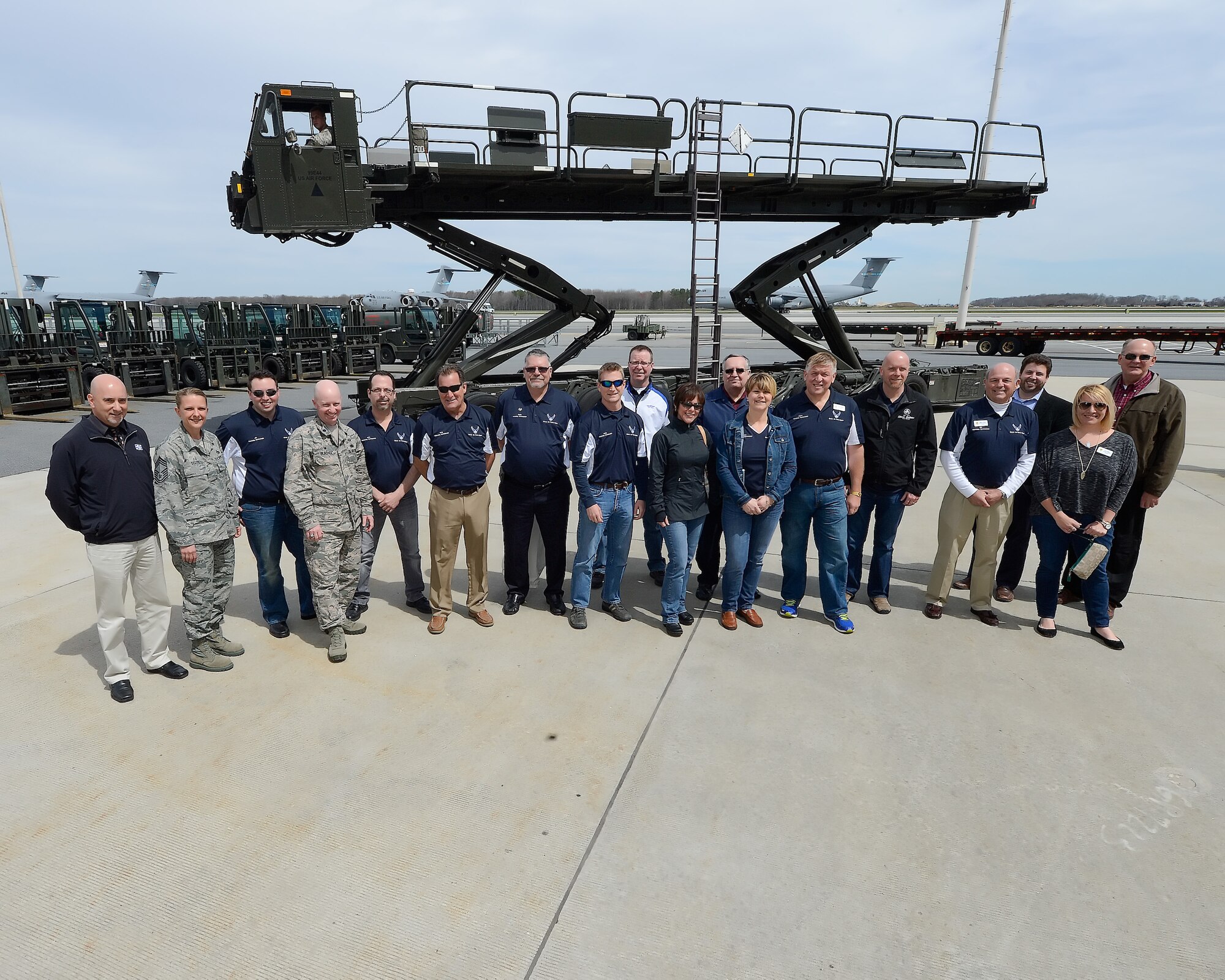The 2015 Dover Air Force Base Honorary Commanders pose with a 60K 'Tunner' cargo transport and loading vehicle during a tour of the 436th Maintenance Group April 15, 2015, on Dover Air Force Base, Del.  C-5M Super Galaxy and C-17A Globemaster III cargo aircraft can be seen in the background. (U.S. Air Force photo/Greg L. Davis)